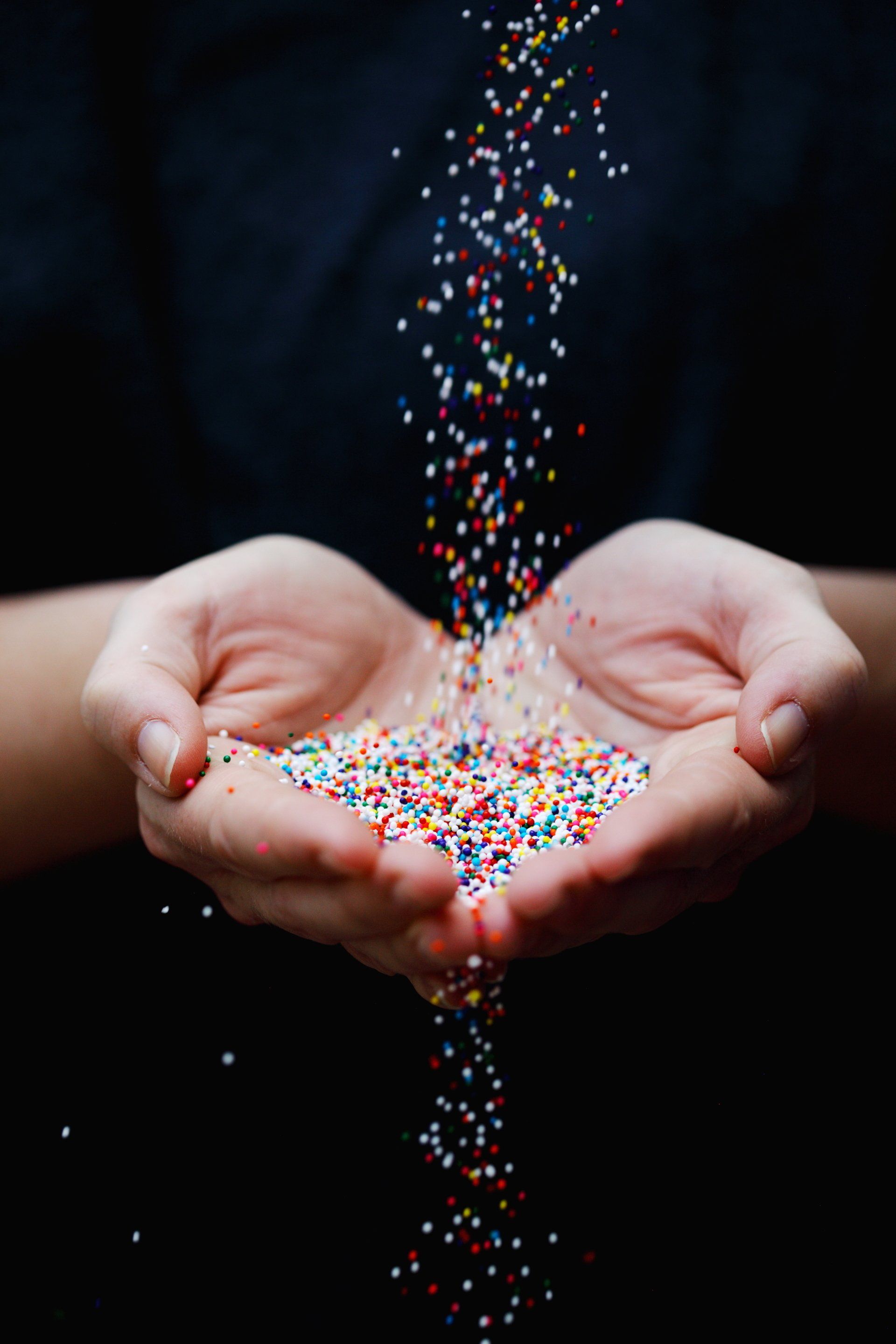 A person is holding a pile of sprinkles in their hands.