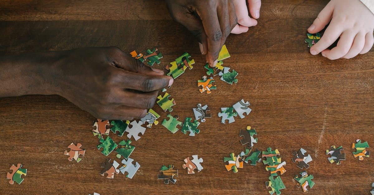 Overhead shot of two pairs of hands assembling a puzzle