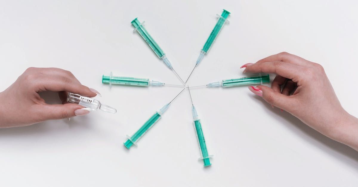 A person is holding a syringe and a bottle of vaccine.