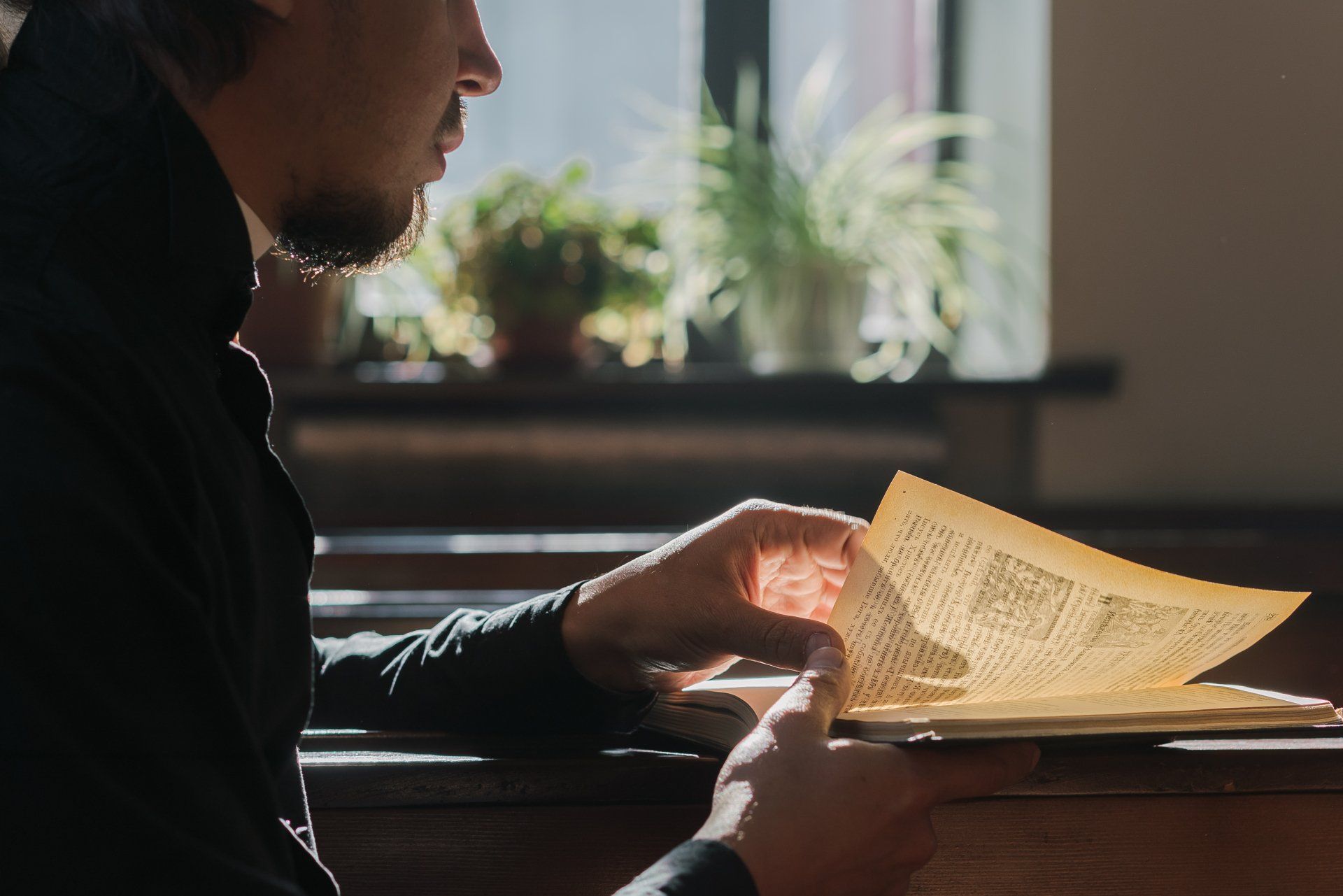 A man is sitting at a table reading a piece of paper.