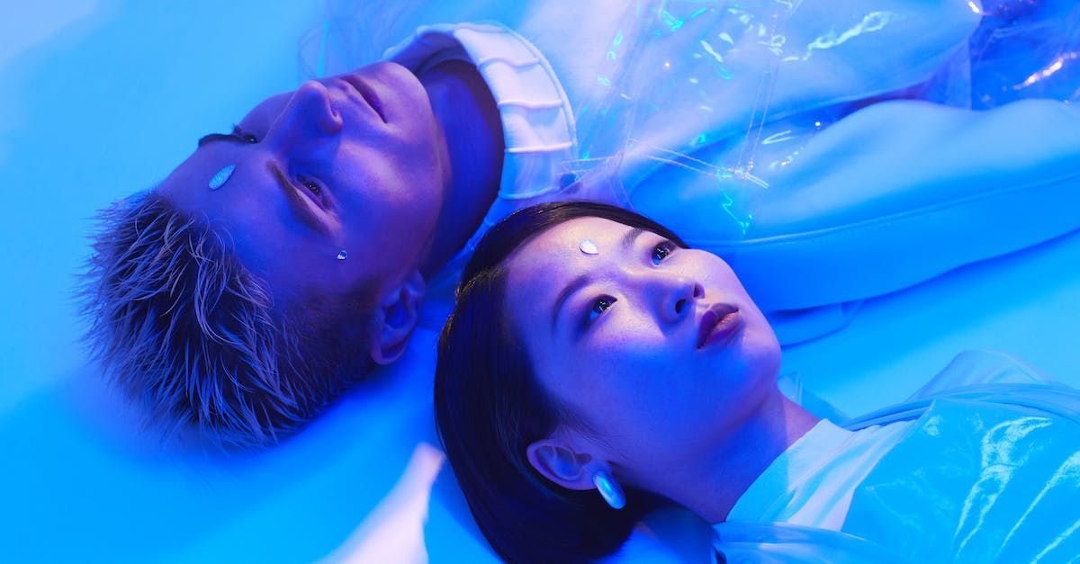 a man and a woman are laying next to each other on a blue surface .