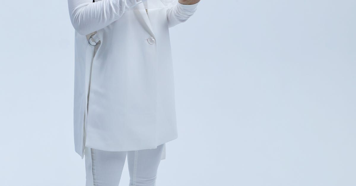 A man in a white coat and white pants is standing in front of a white background.