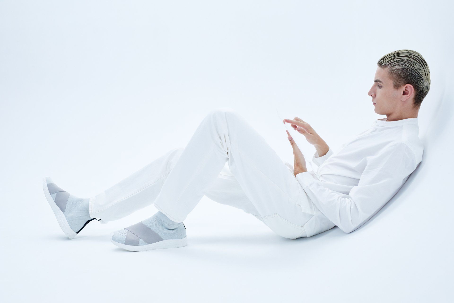 a man in all white sits on a white surface with his legs crossed The Agency Kansas City