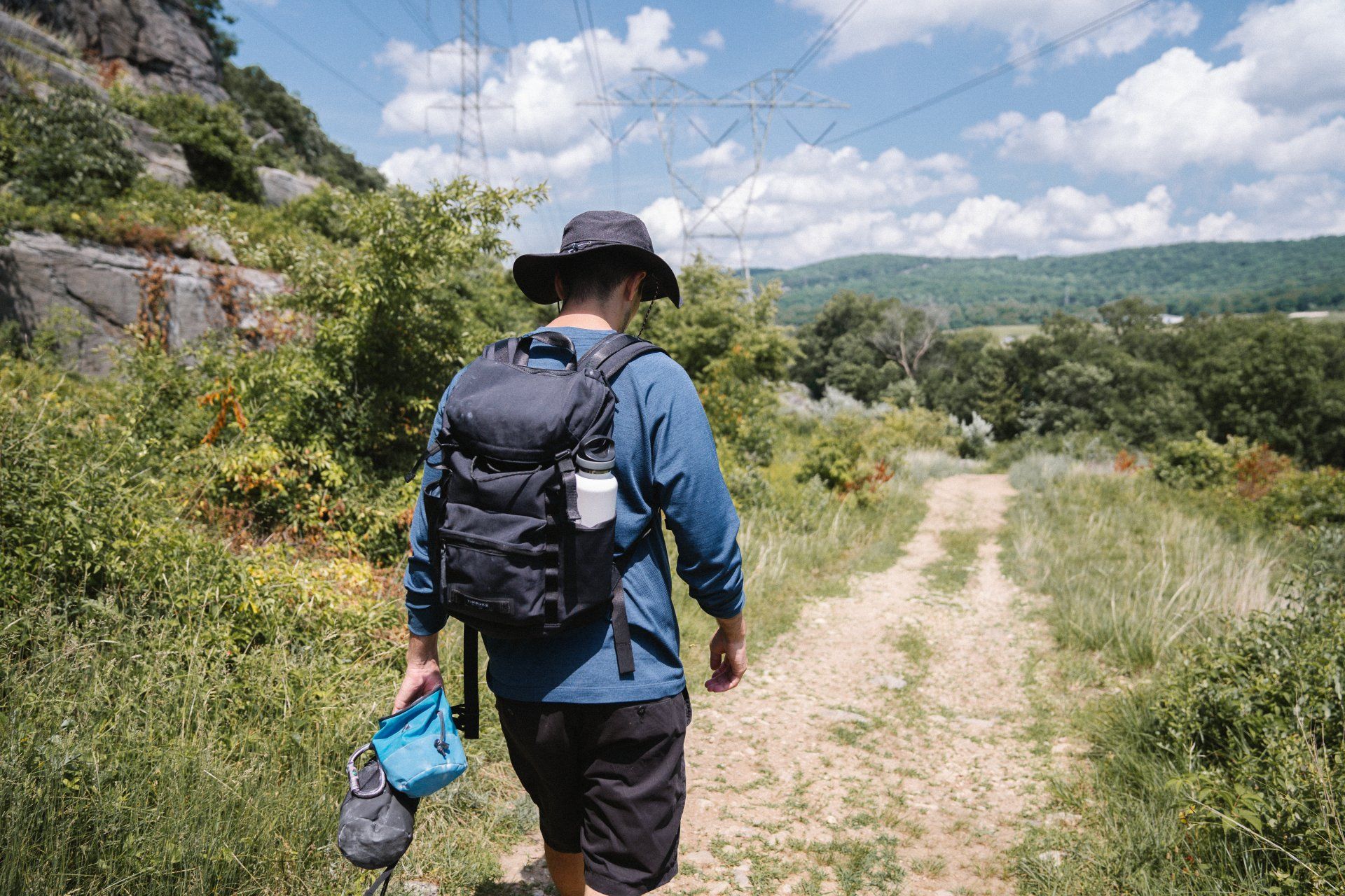 A man with a backpack is walking down a dirt path.