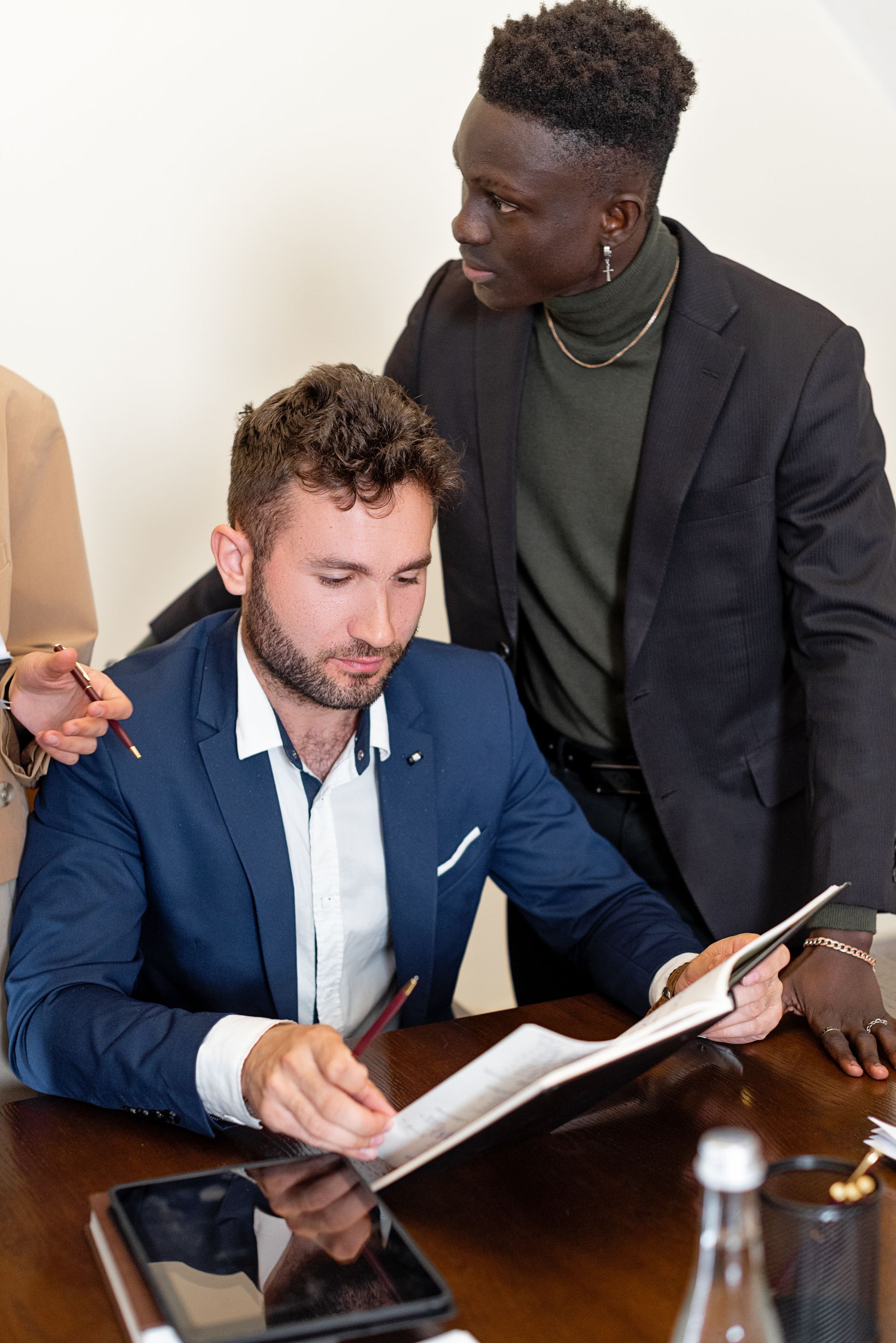 A man in a suit is sitting at a table looking at a piece of paper.