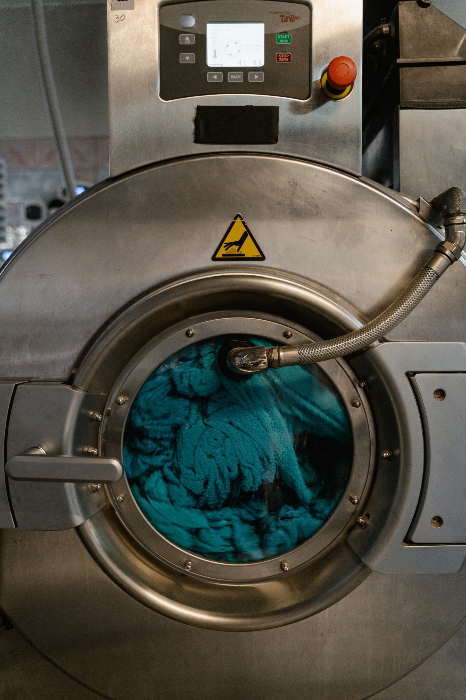 Person using a multimeter to test a washing machine's internal components. Tools and parts are visible on top.
