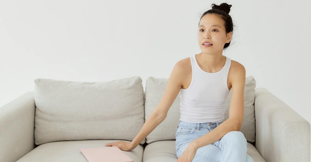 A woman is sitting on a couch with a laptop.