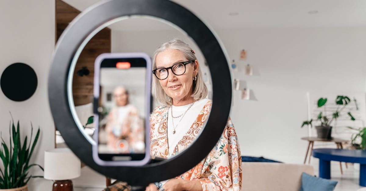 A woman is holding a cell phone in front of a ring light.