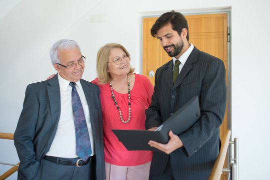 an accountant in a suit holds a clipboard in front of a couple