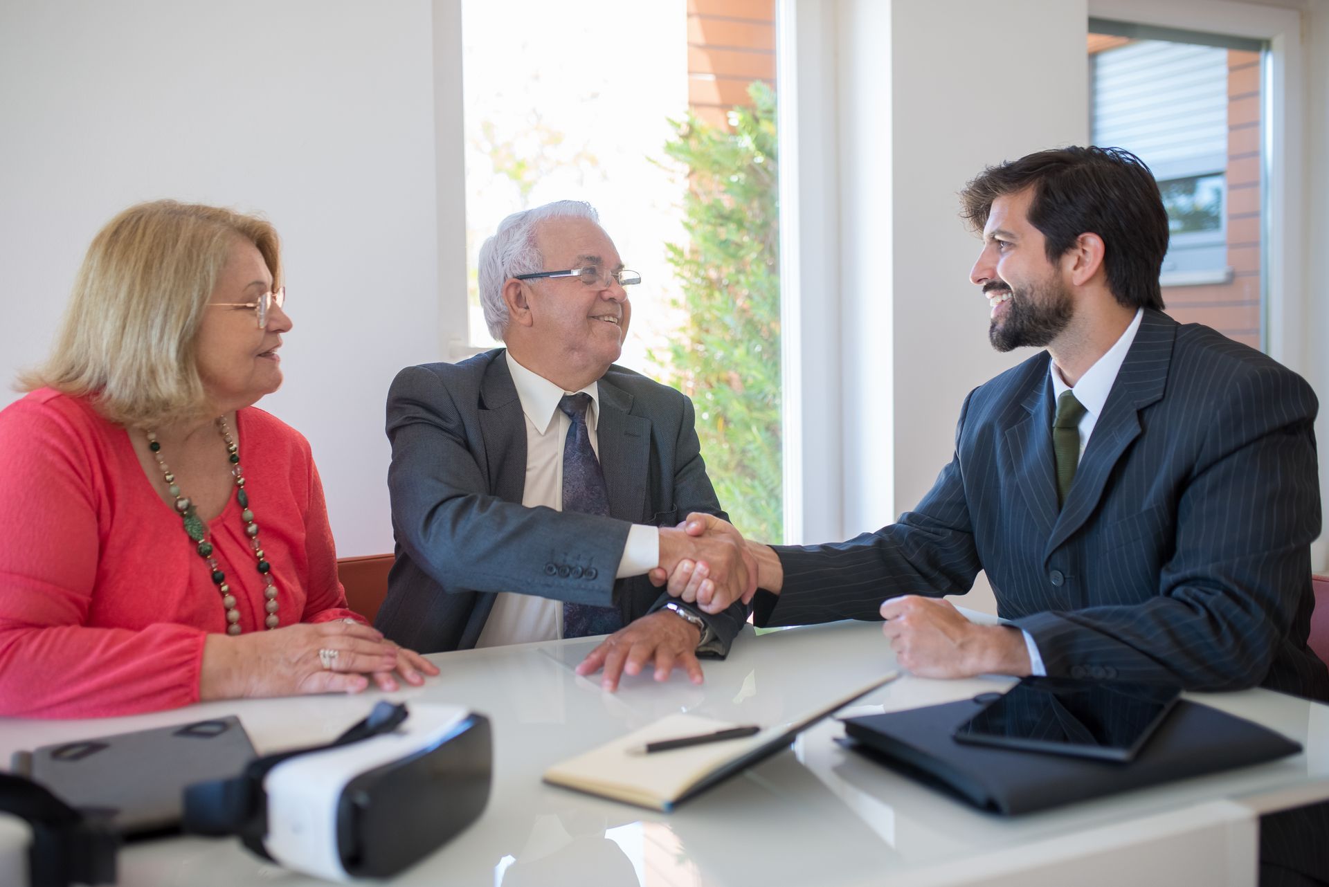 A man and woman are shaking hands with a businessman while sitting at a table.