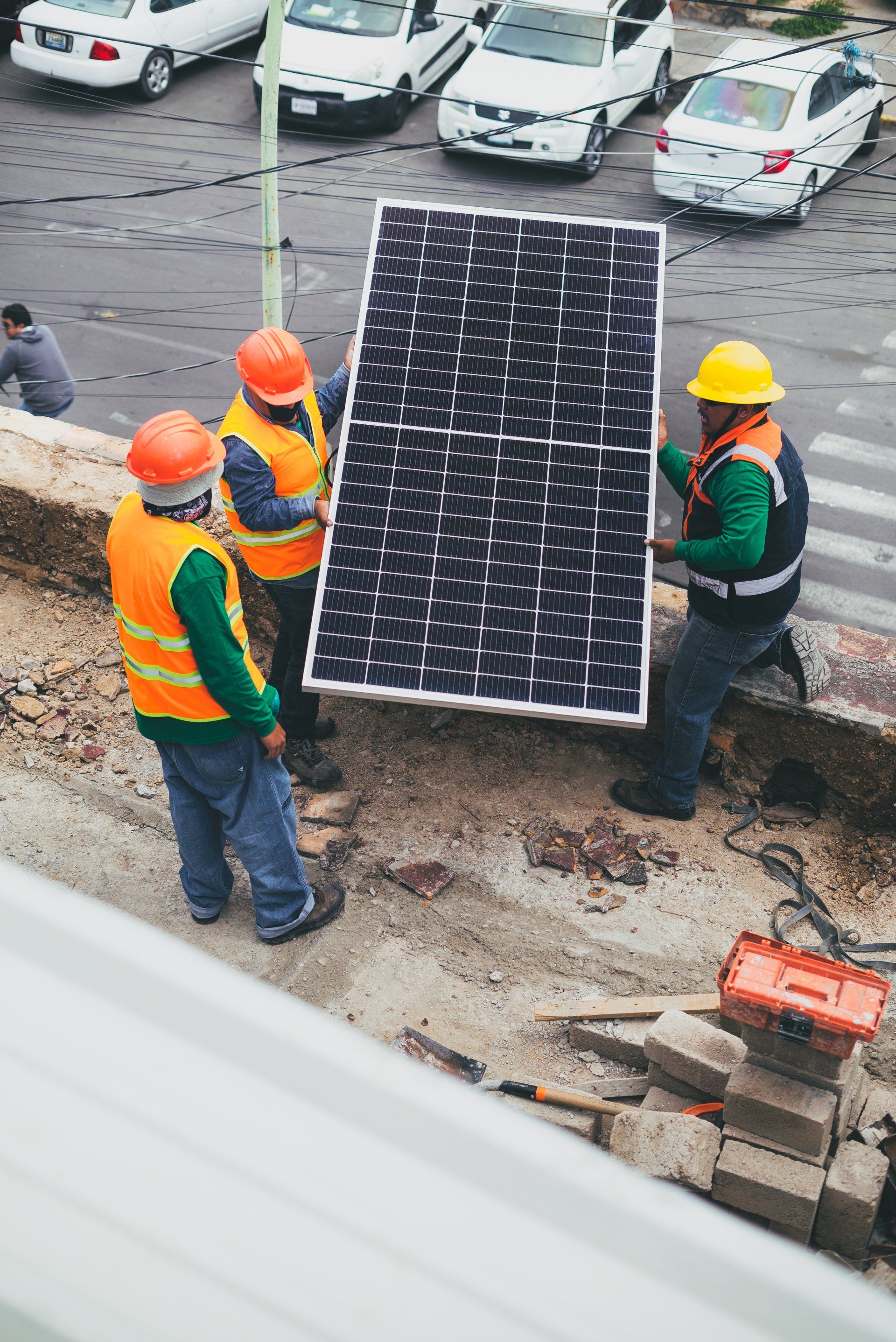 Un grupo de trabajadores de la construcción transporta un gran panel solar.