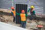 A group of construction workers are installing a solar panel.