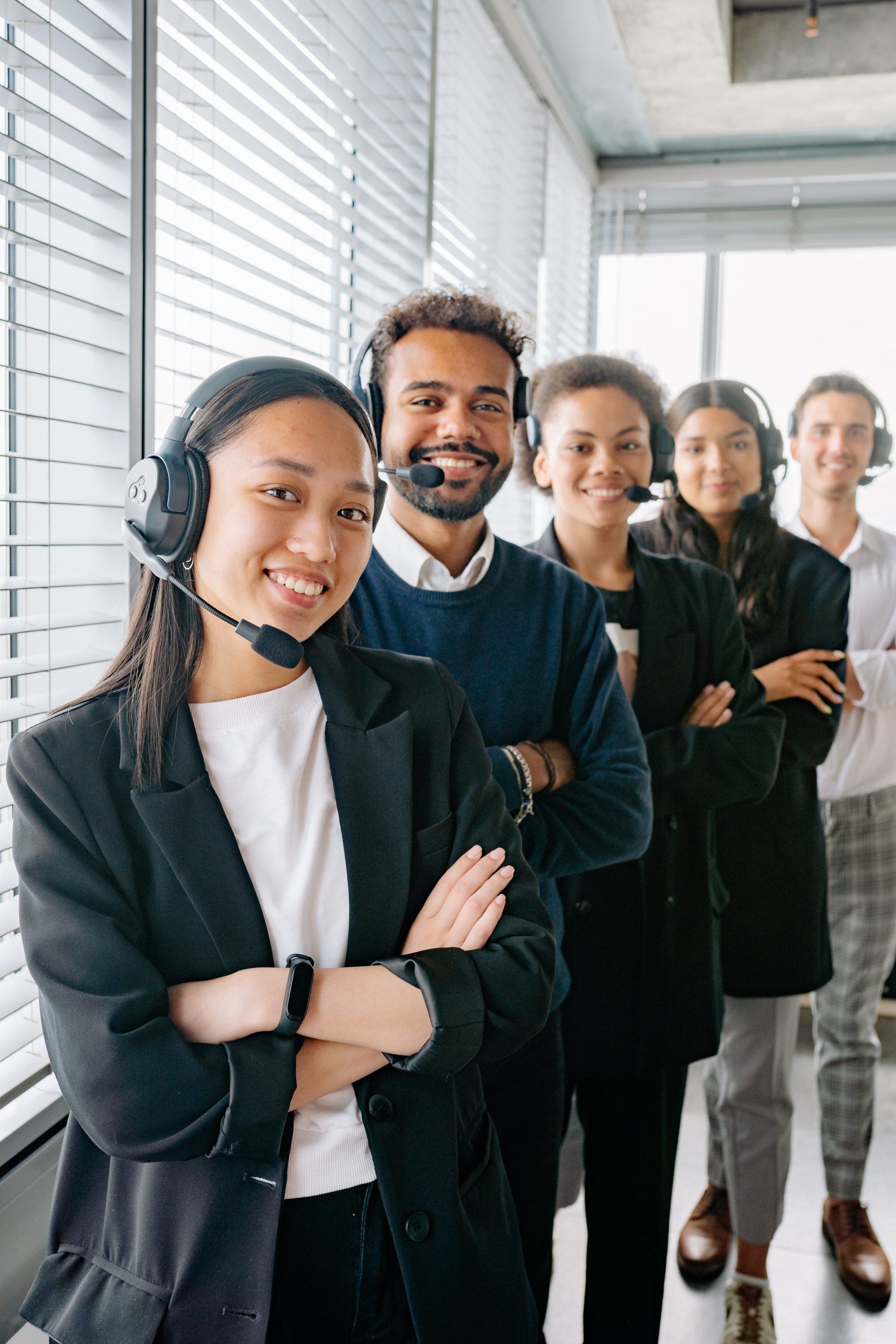 A group of people wearing headsets are standing next to each other in an office.