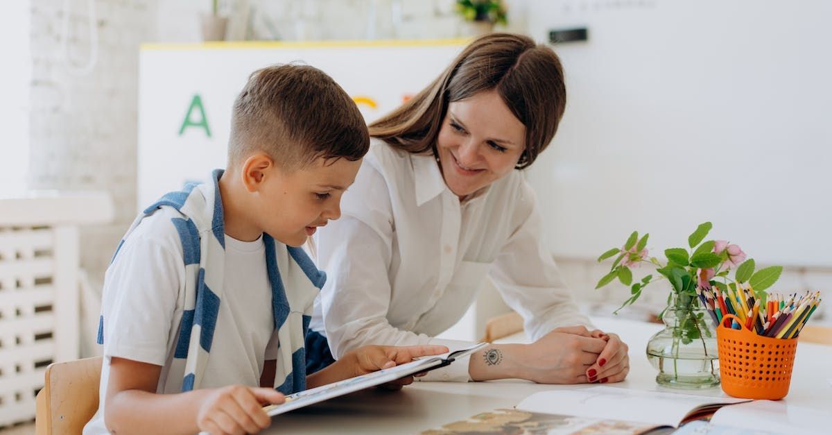 A woman is helping a young boy with his homework.