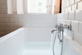 A bathtub with water running from the faucet in a bathroom.