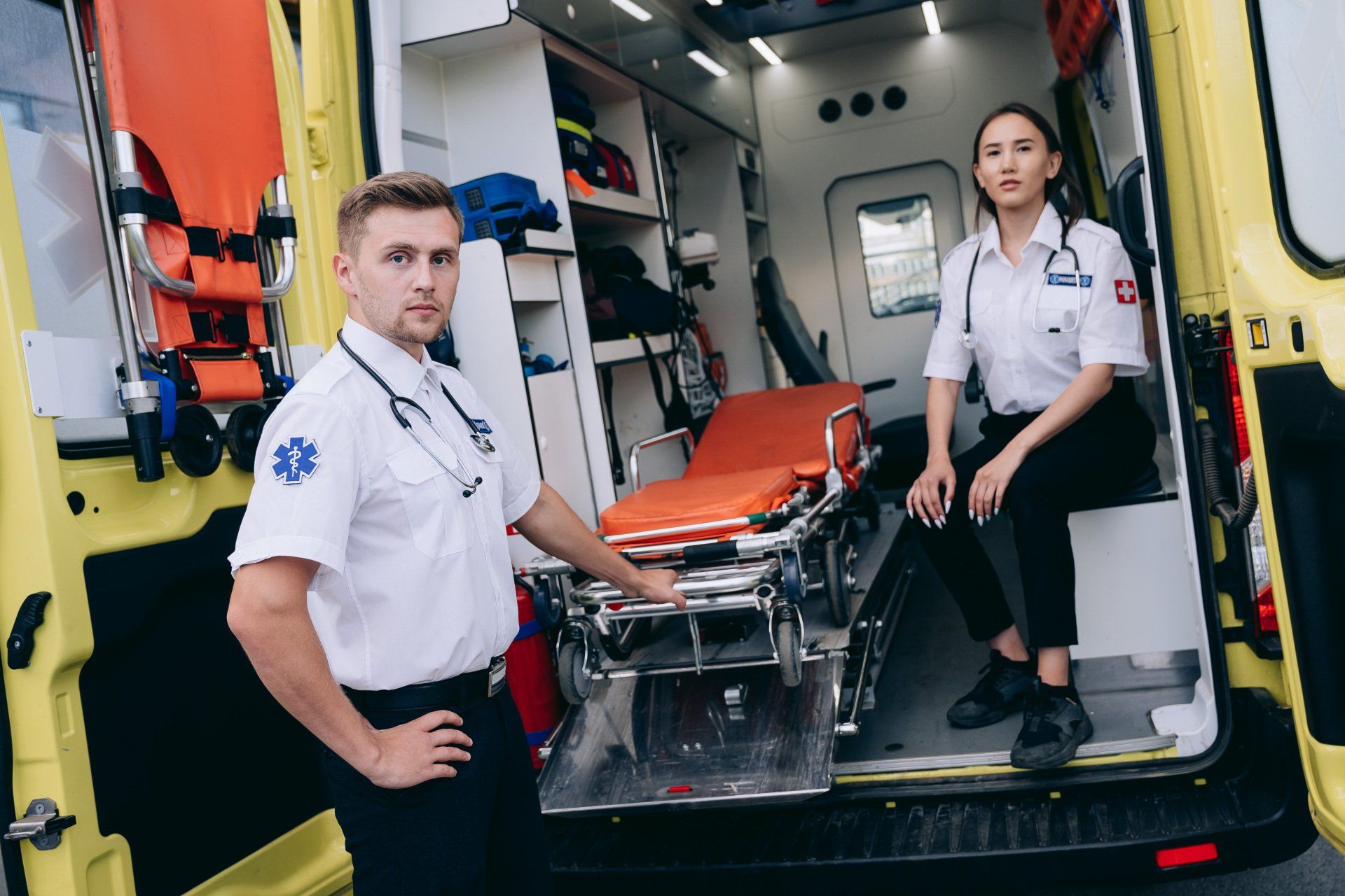 two paramedics sitting at the back of an ambulance with the doors open