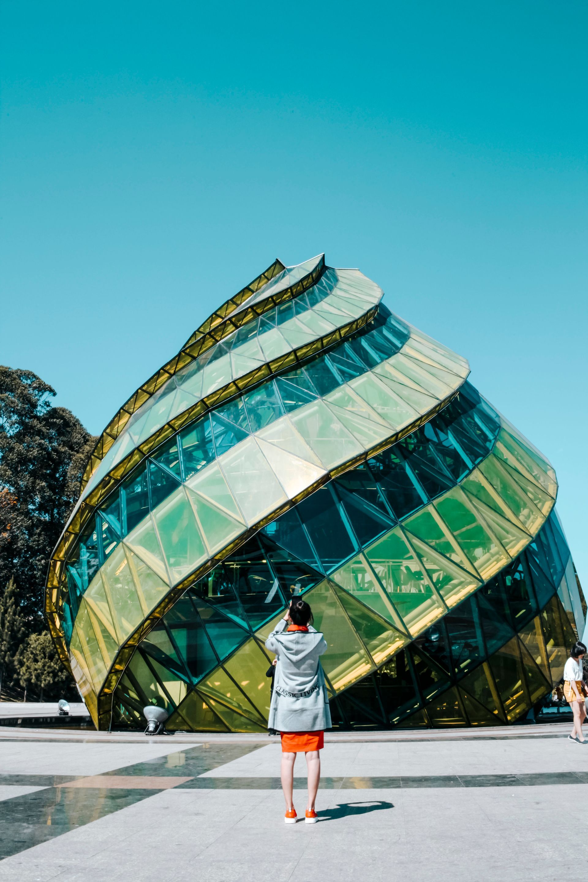 A man is standing in front of a large green and gold building.