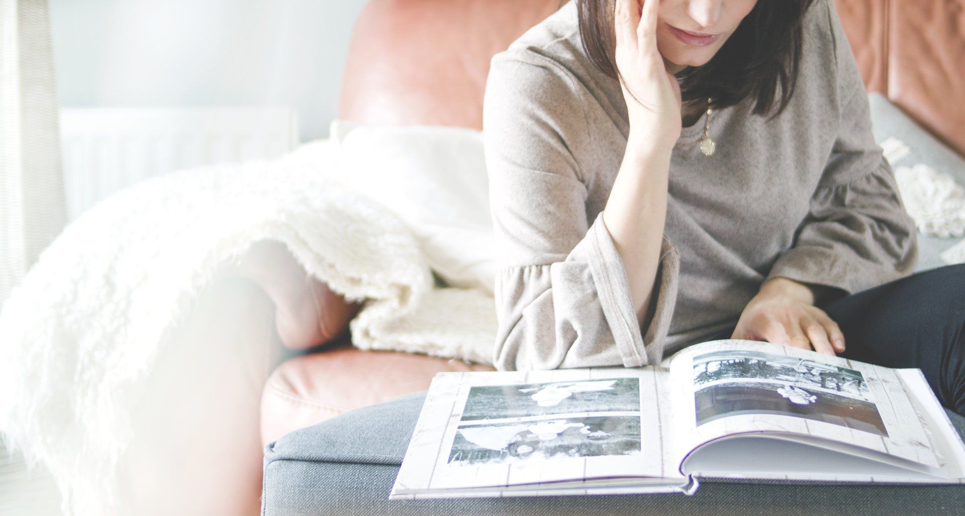 A woman is sitting on a couch reading a book.