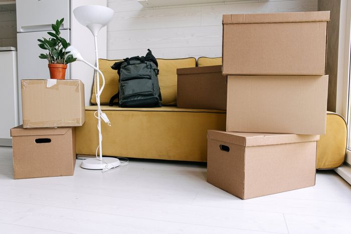 A living room filled with cardboard boxes and a yellow couch.