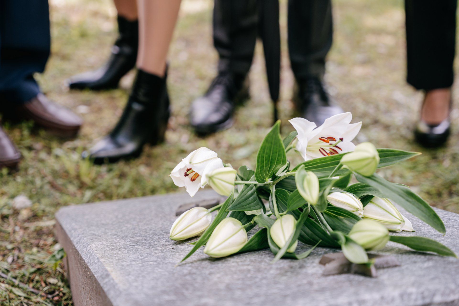 Een groep mensen staat rond een graf met bloemen erop.