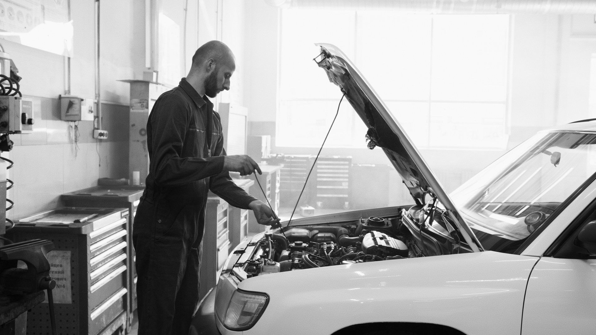 A man is working on a car in a garage with the hood open.  | Evolution Auto Service