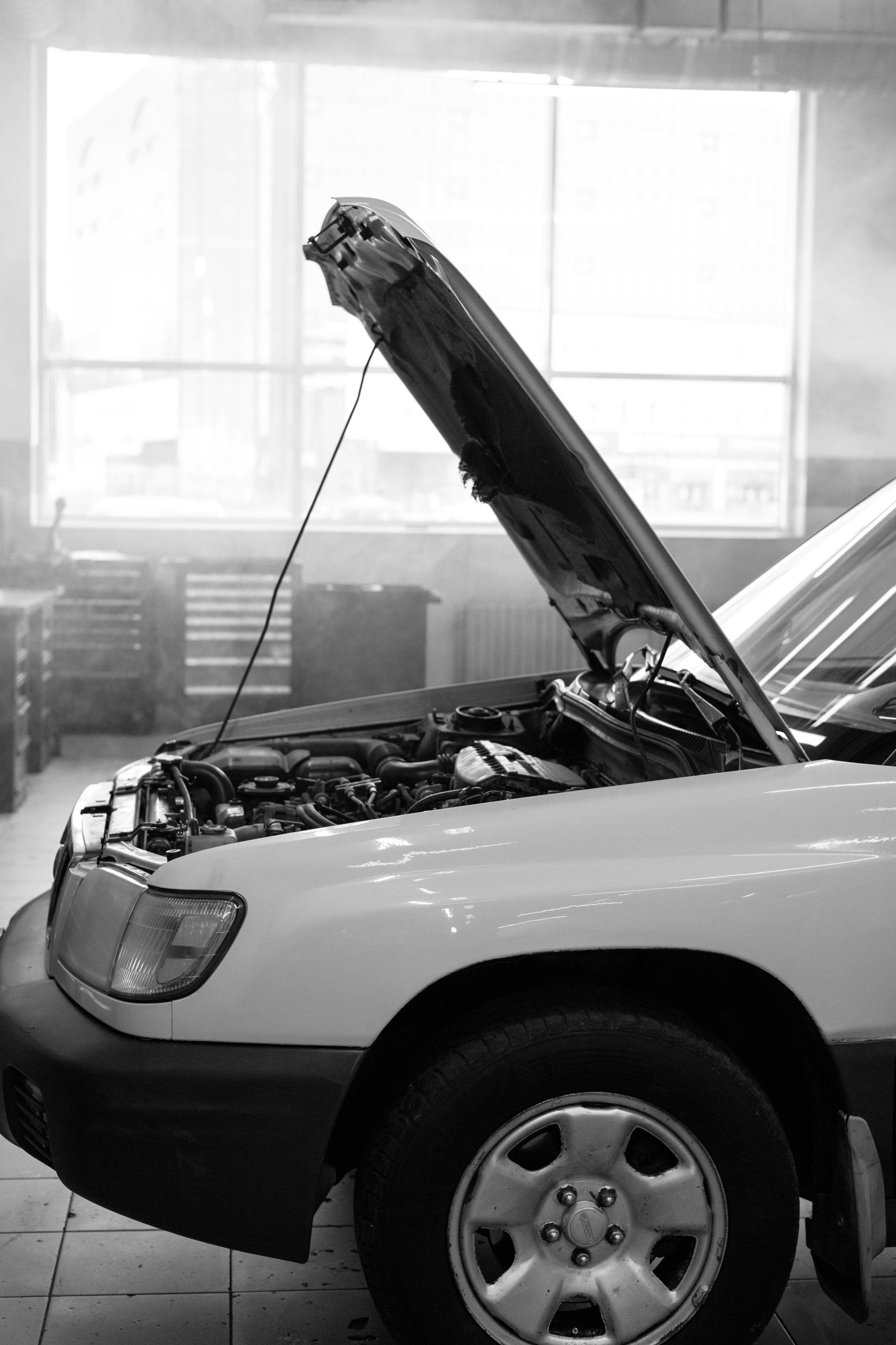 A car with the hood up sittong in a garage