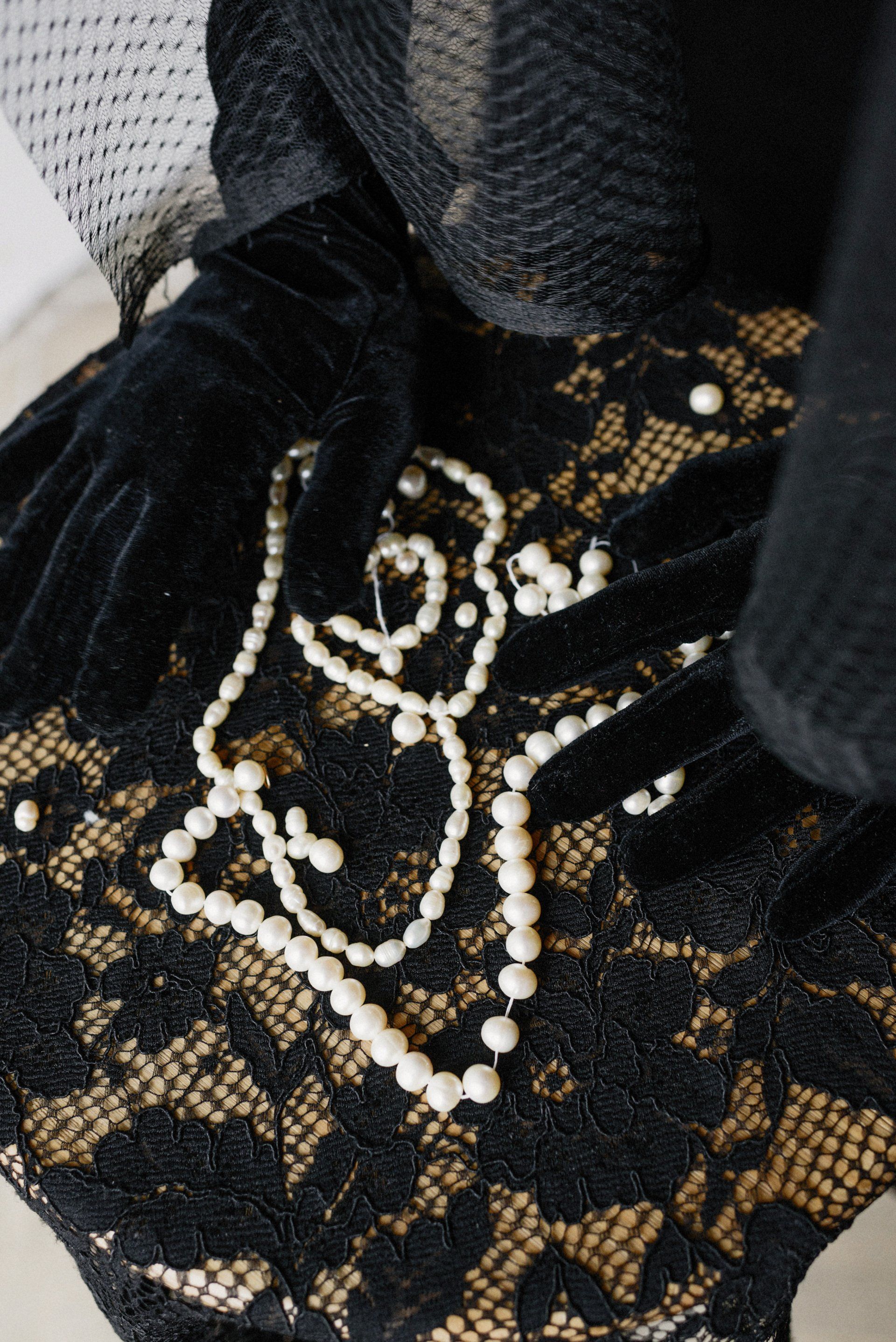 a pearl necklace and earrings are on a black lace cloth