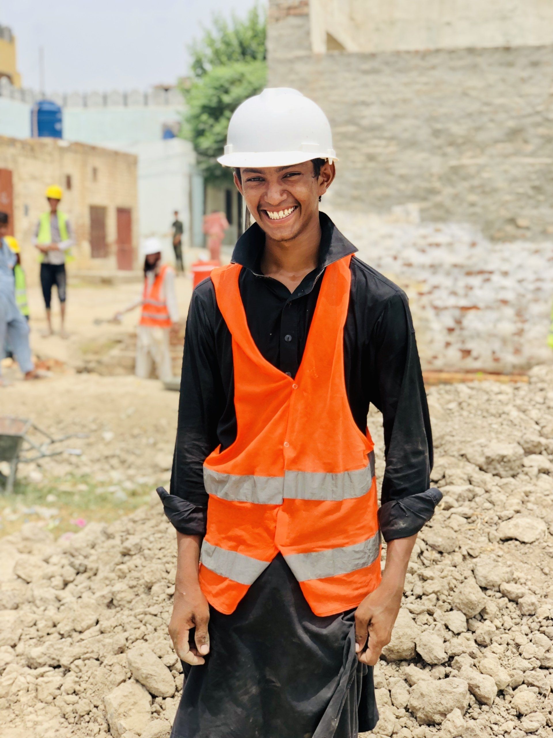 A man wearing an orange vest and a white hard hat