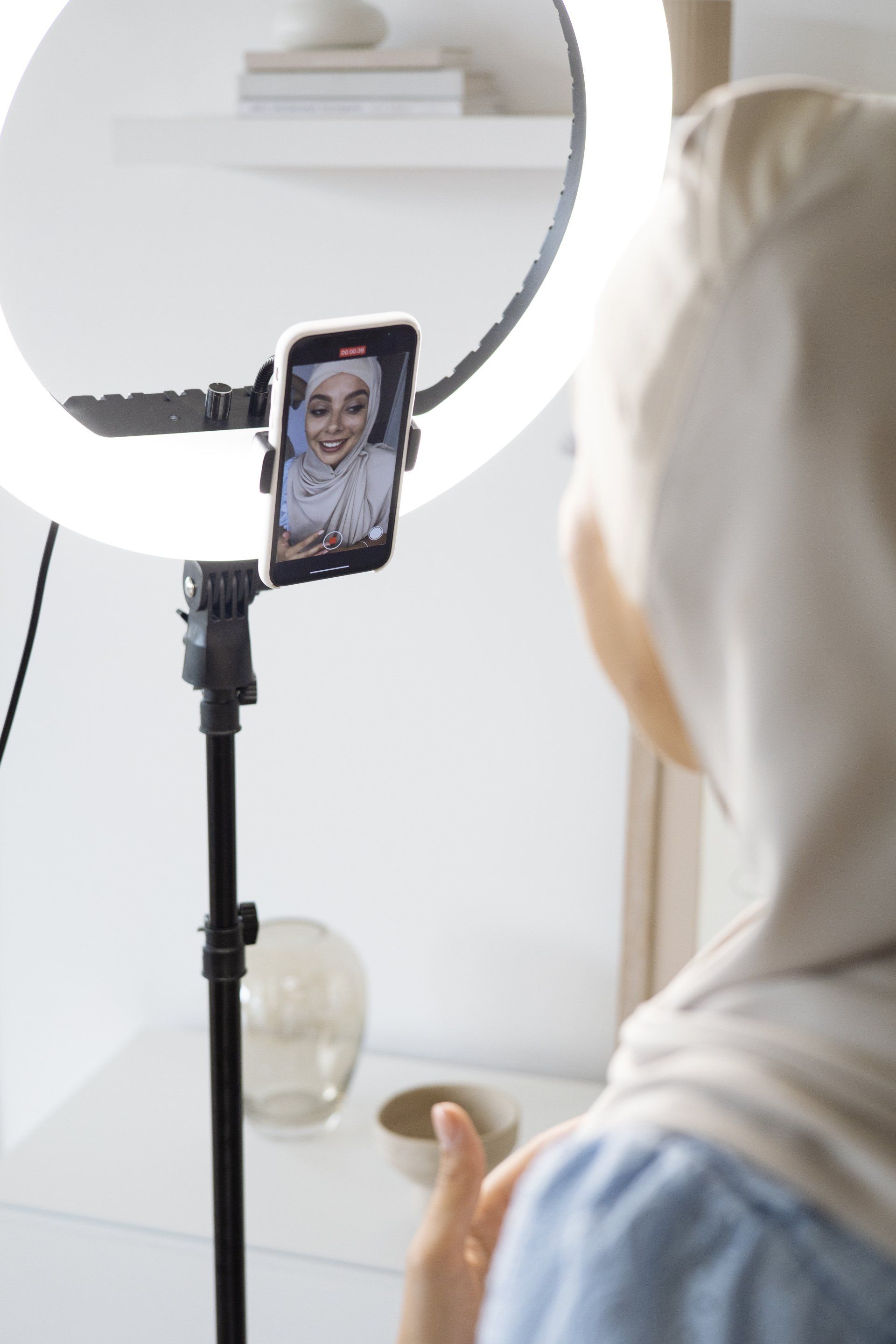 A woman is taking a picture of herself in front of a ring light.