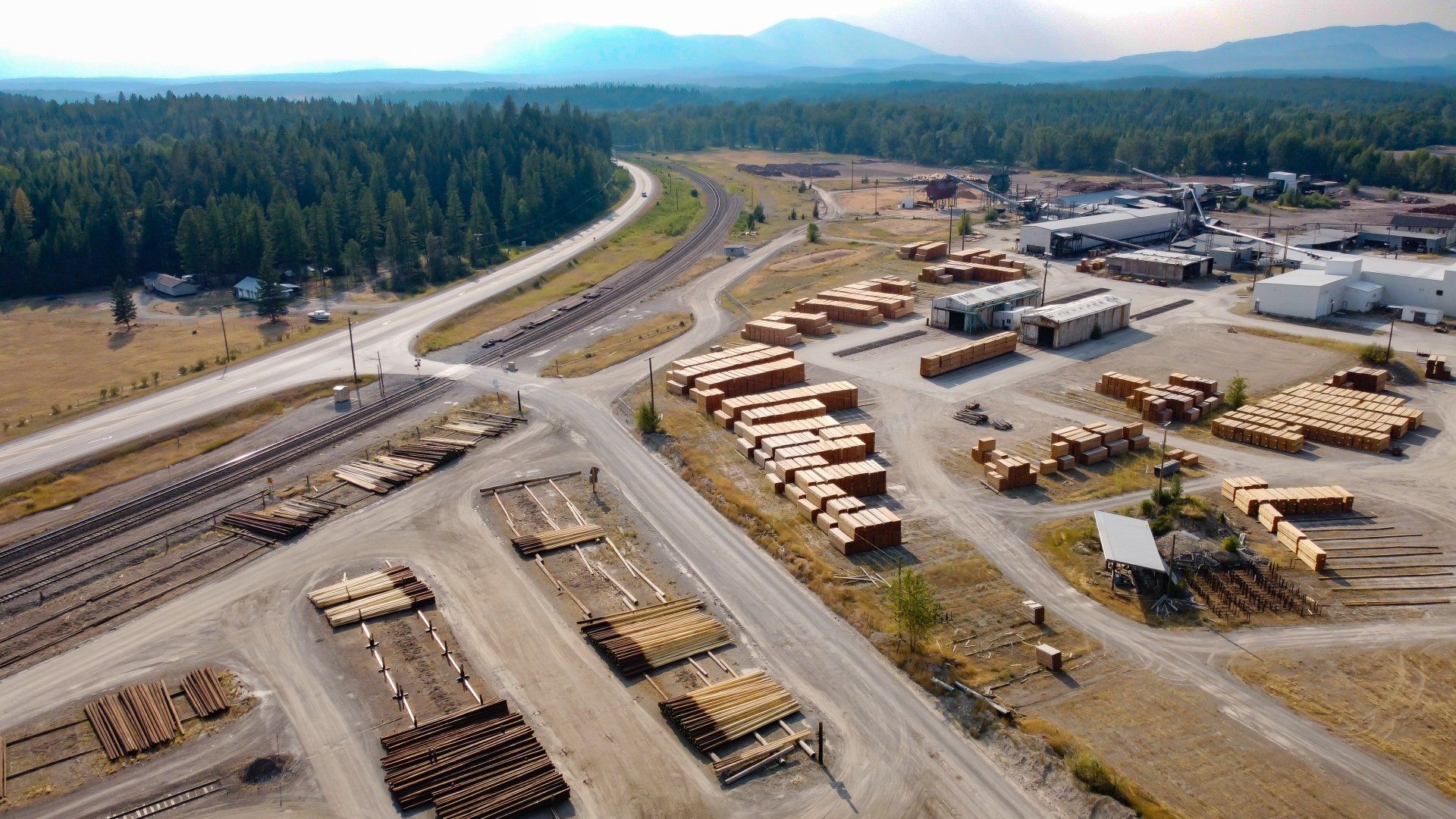 an aerial view of a lumber yard surrounded by trees and a highway .