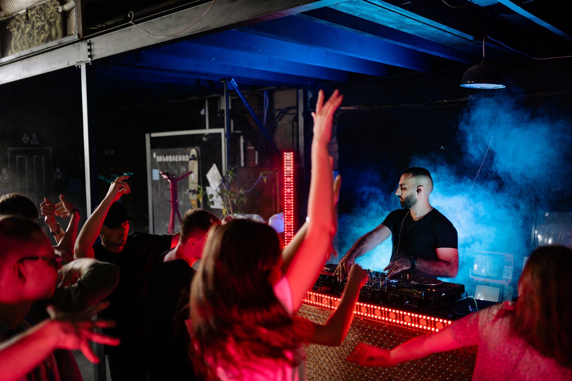 DJ Spinning on DJ Mixer with audience Dancing to the Music with Red & Blue Light