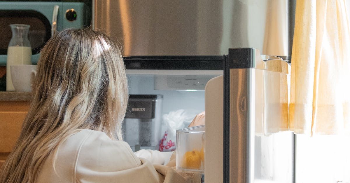a woman is opening a refrigerator door in a kitchen .