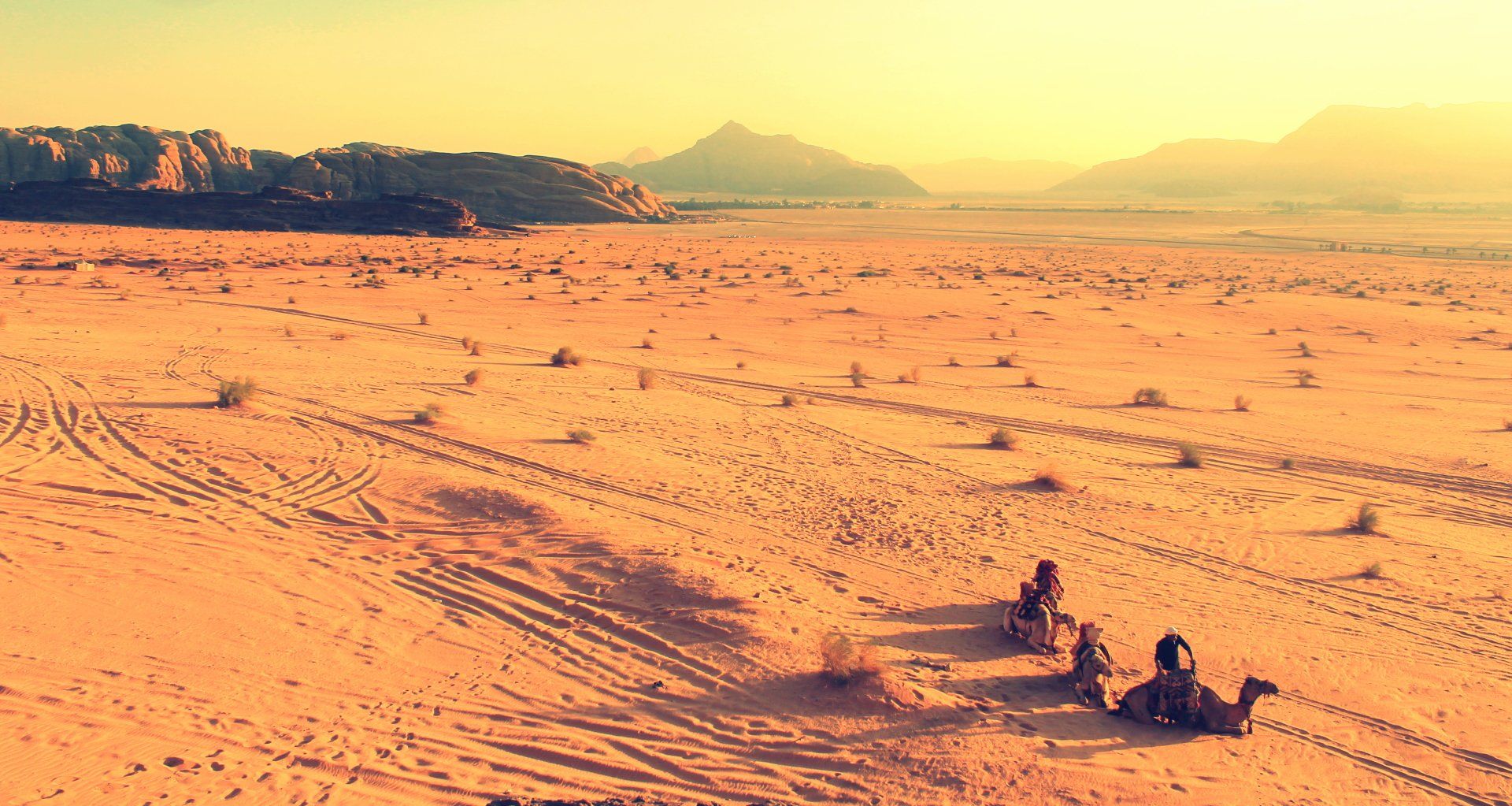 A group of people are riding camels in the desert.