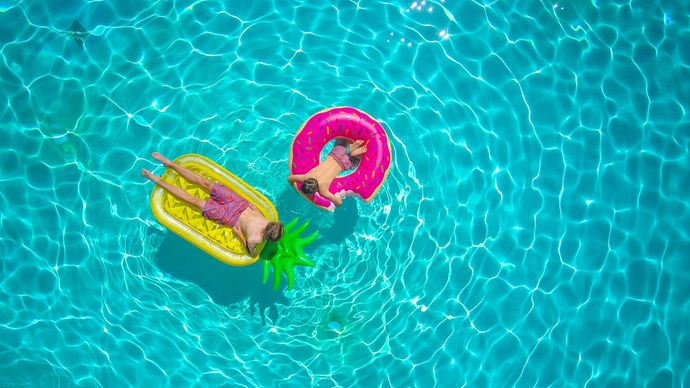 A man and a woman are floating on rafts in a swimming pool.