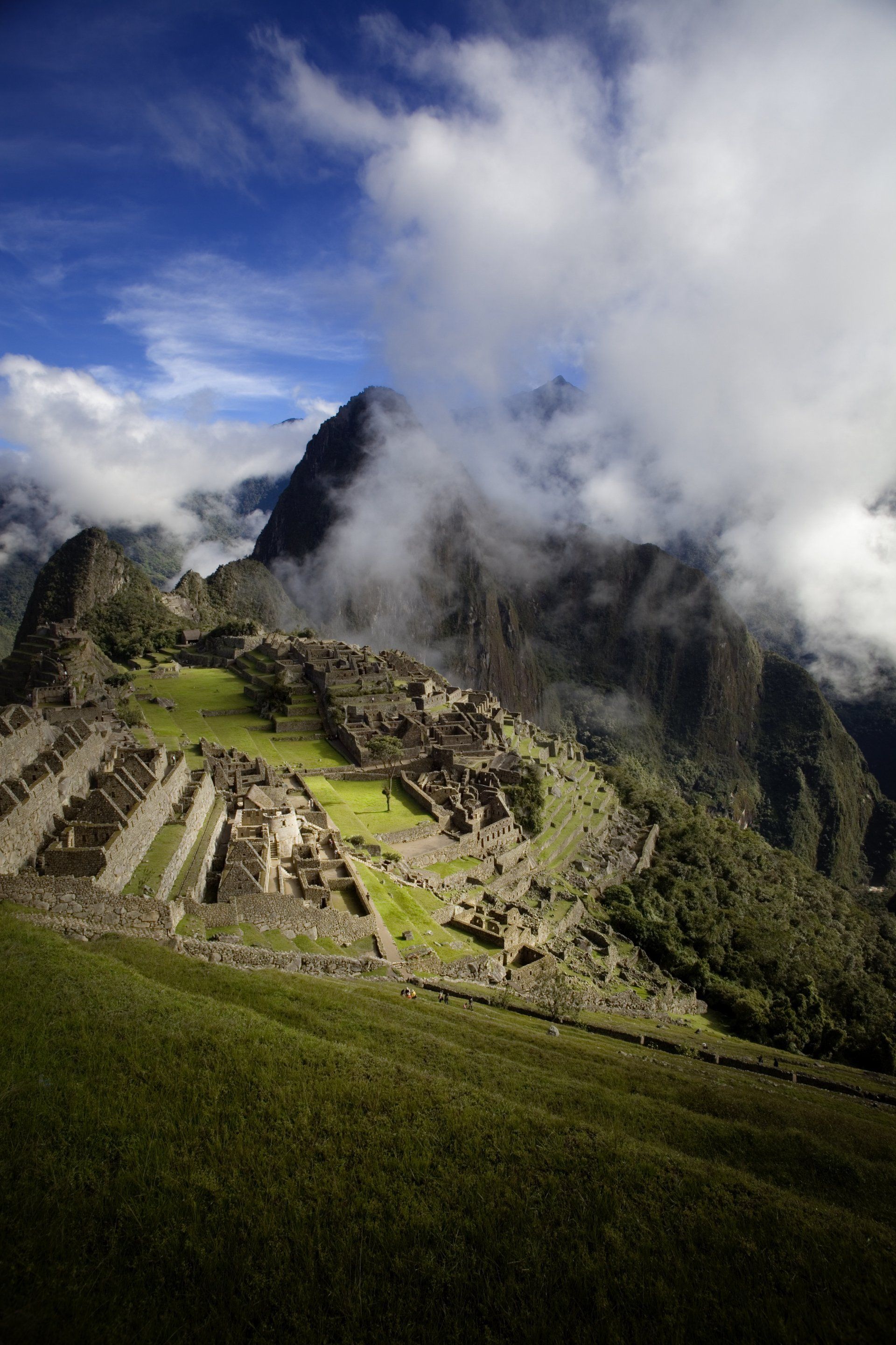 Una montaña cubierta de nubes con una ciudad en ruinas en la distancia.