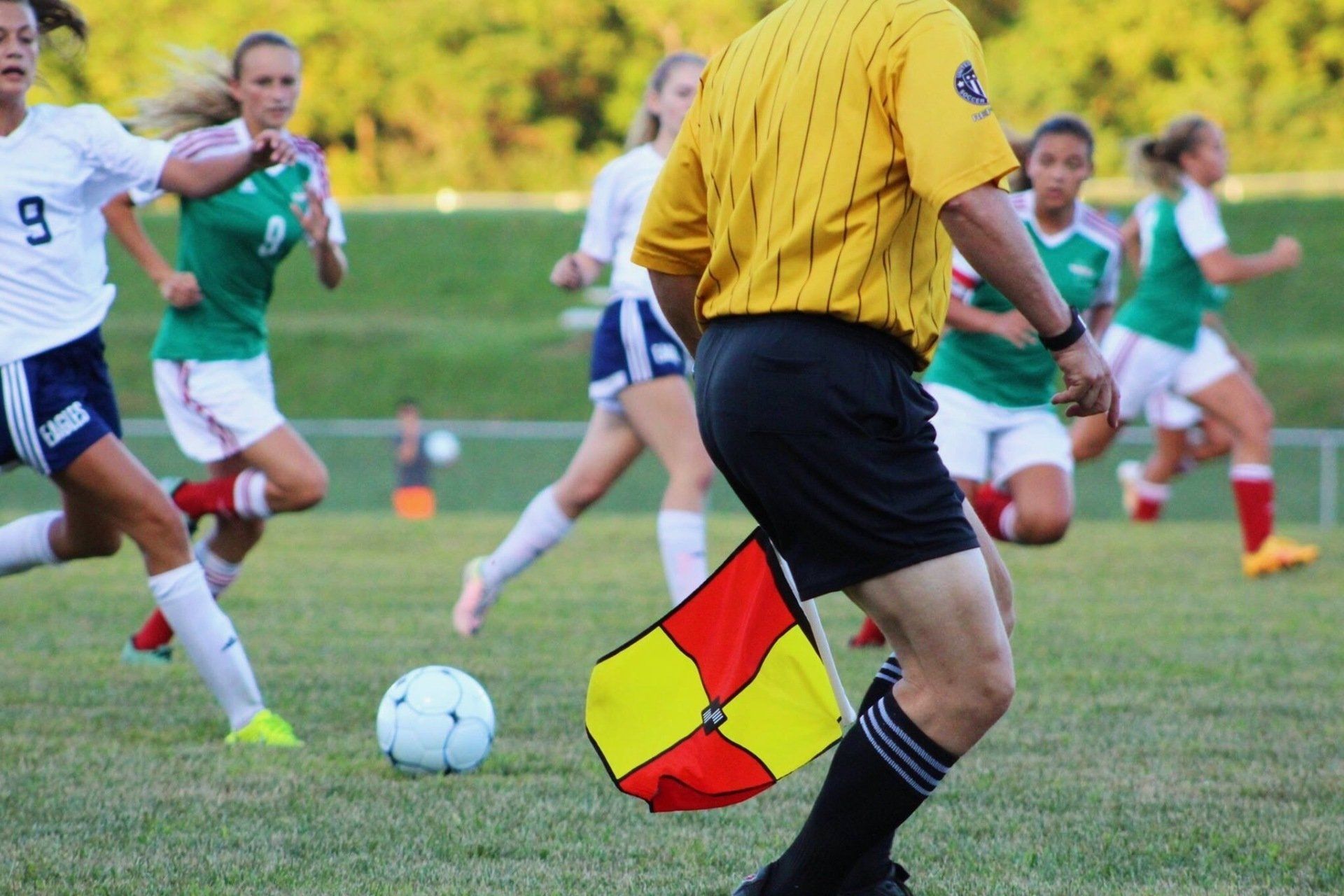 a referee is holding a red and yellow flag while playing soccer .