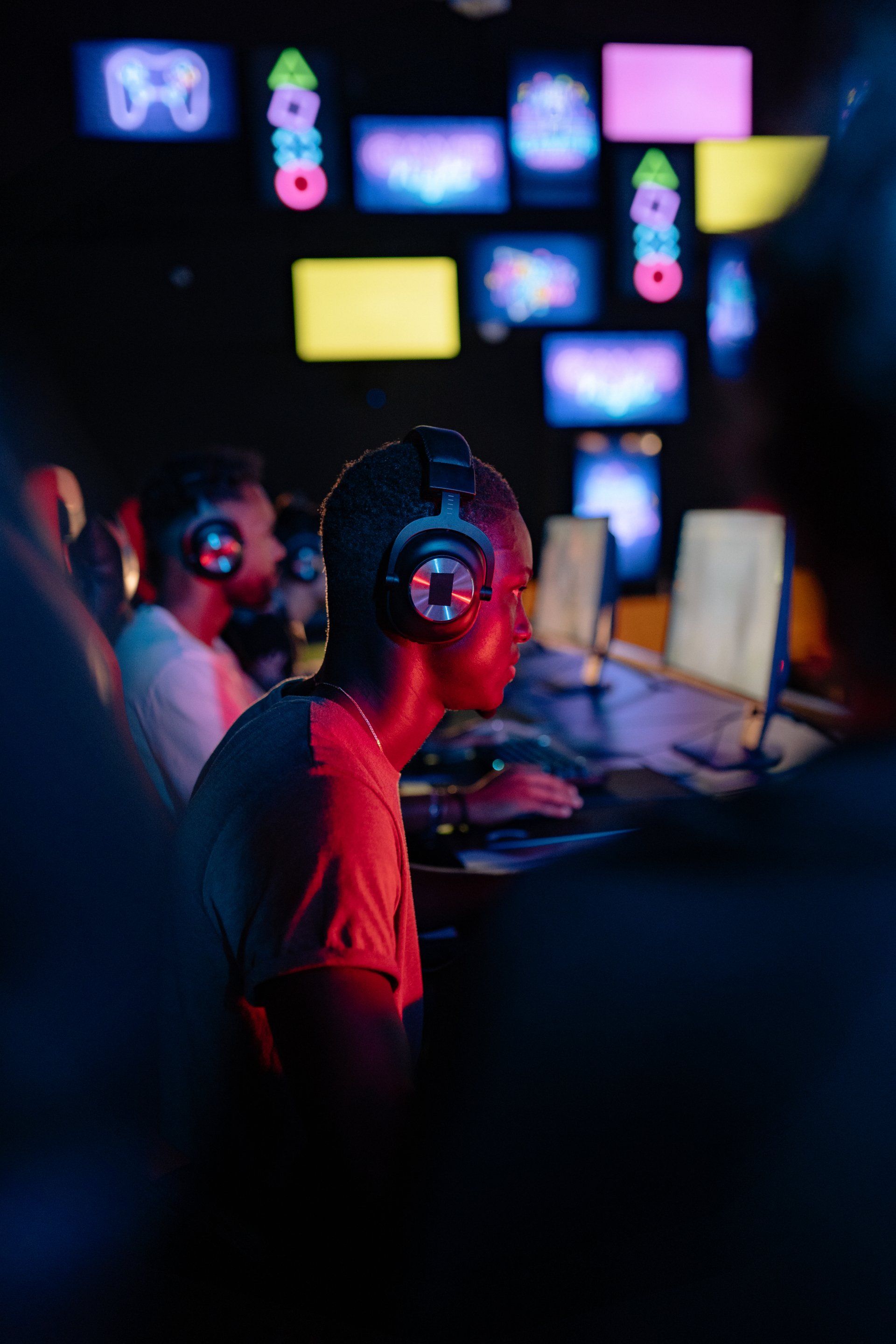 A man wearing headphones is playing a video game in a dark room.