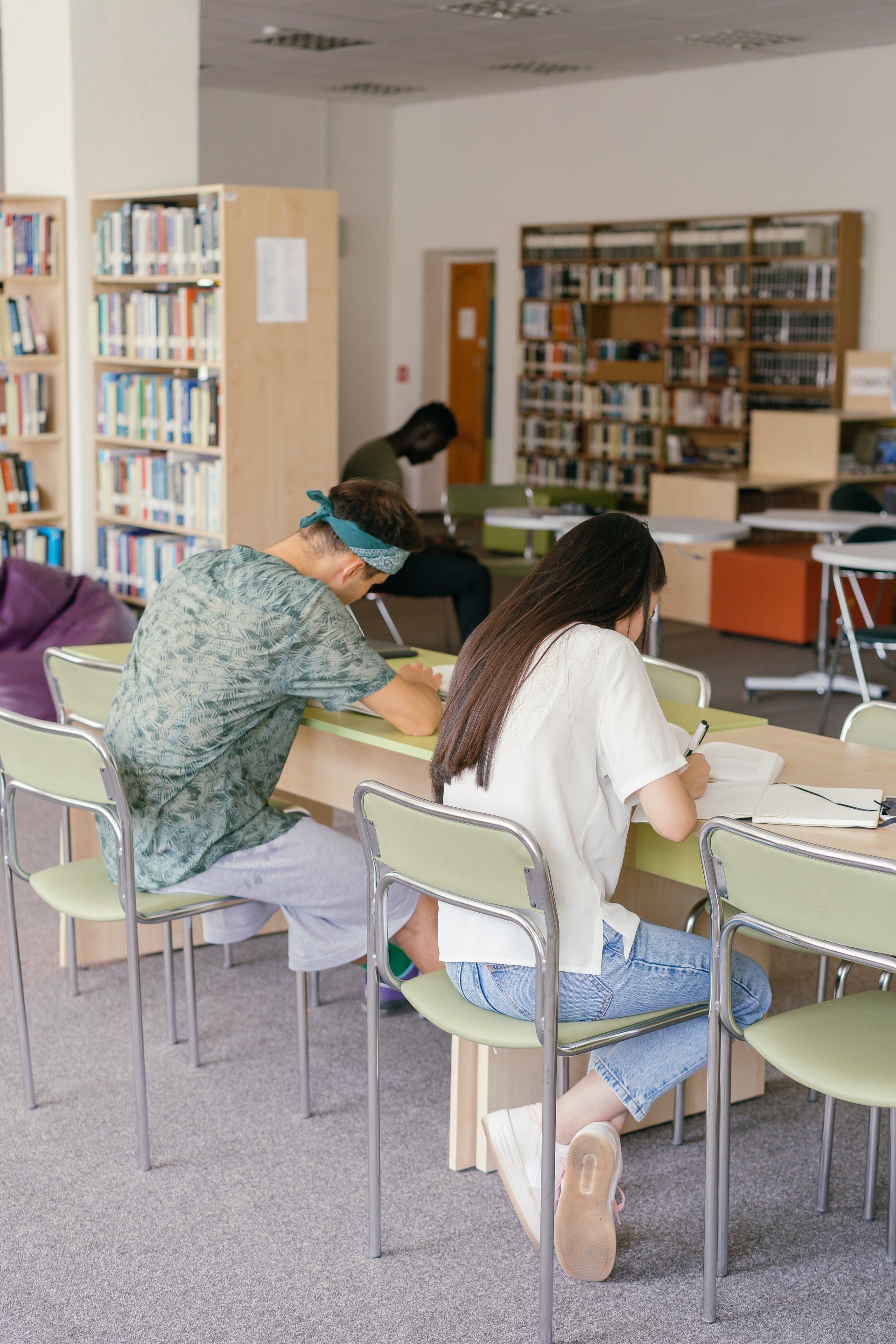 A group of people are sitting at tables in a library.