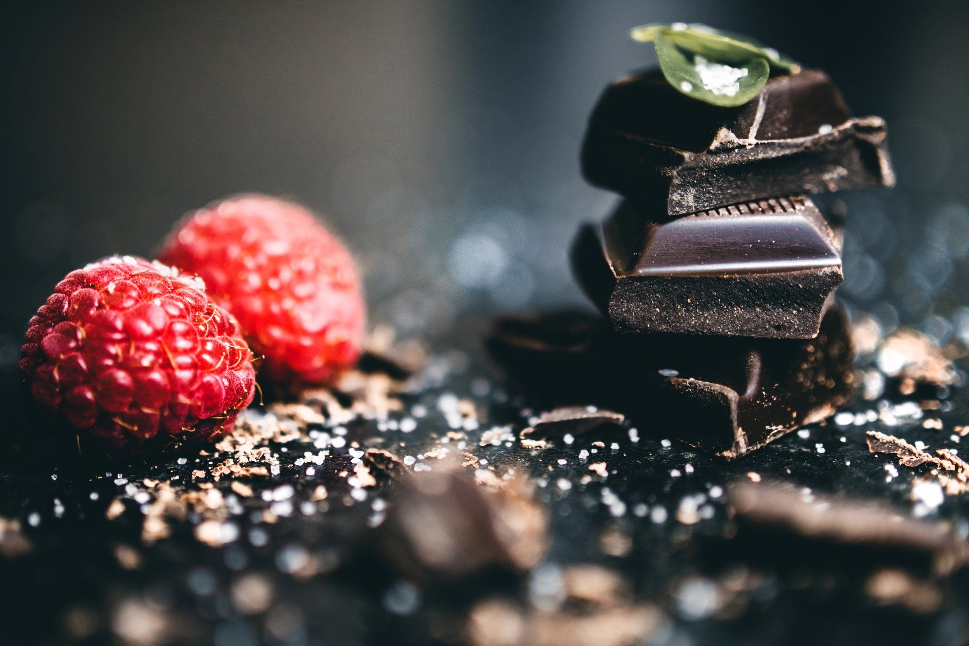 A stack of chocolate bars and raspberries on a table.