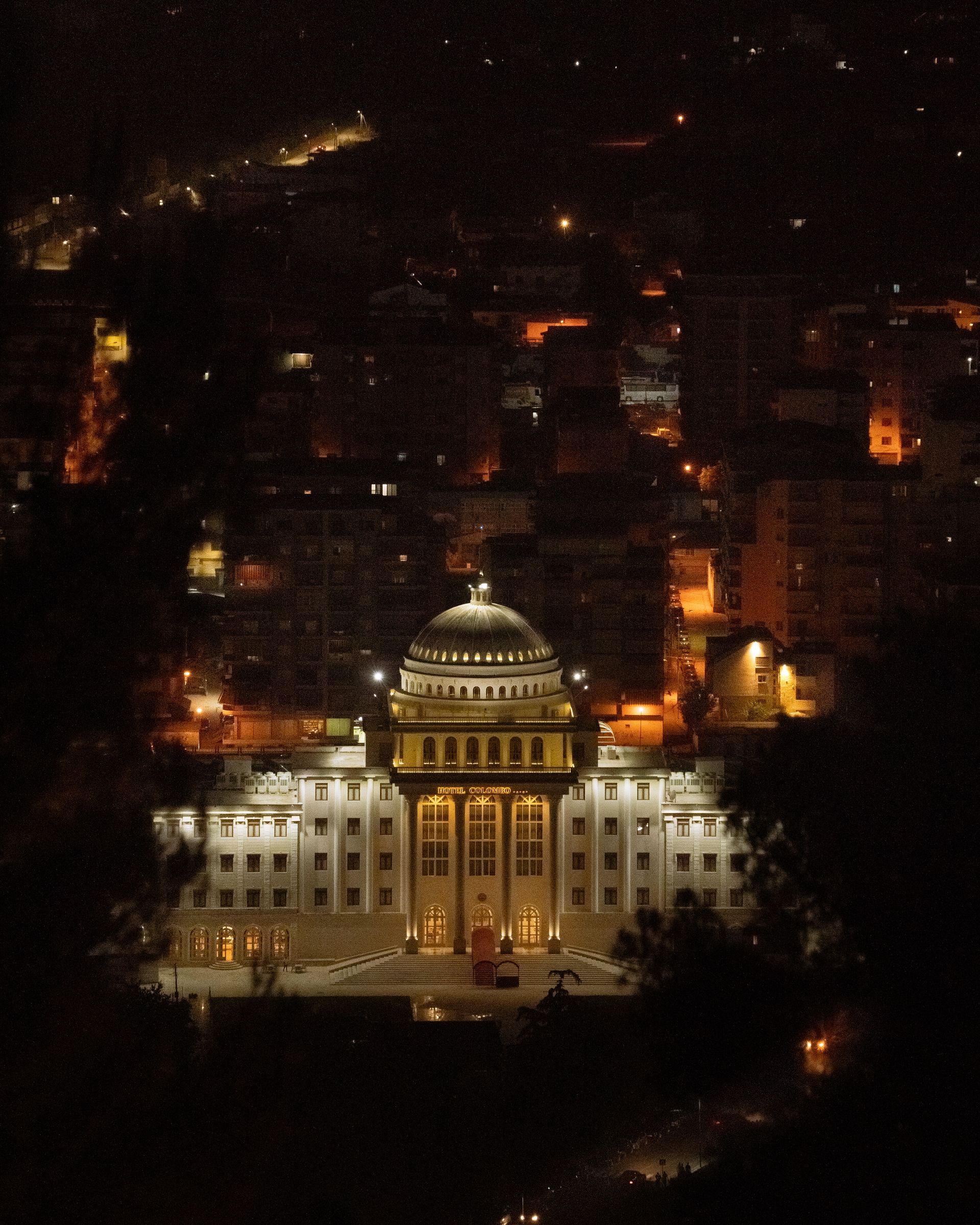 A large building with a dome is lit up at night