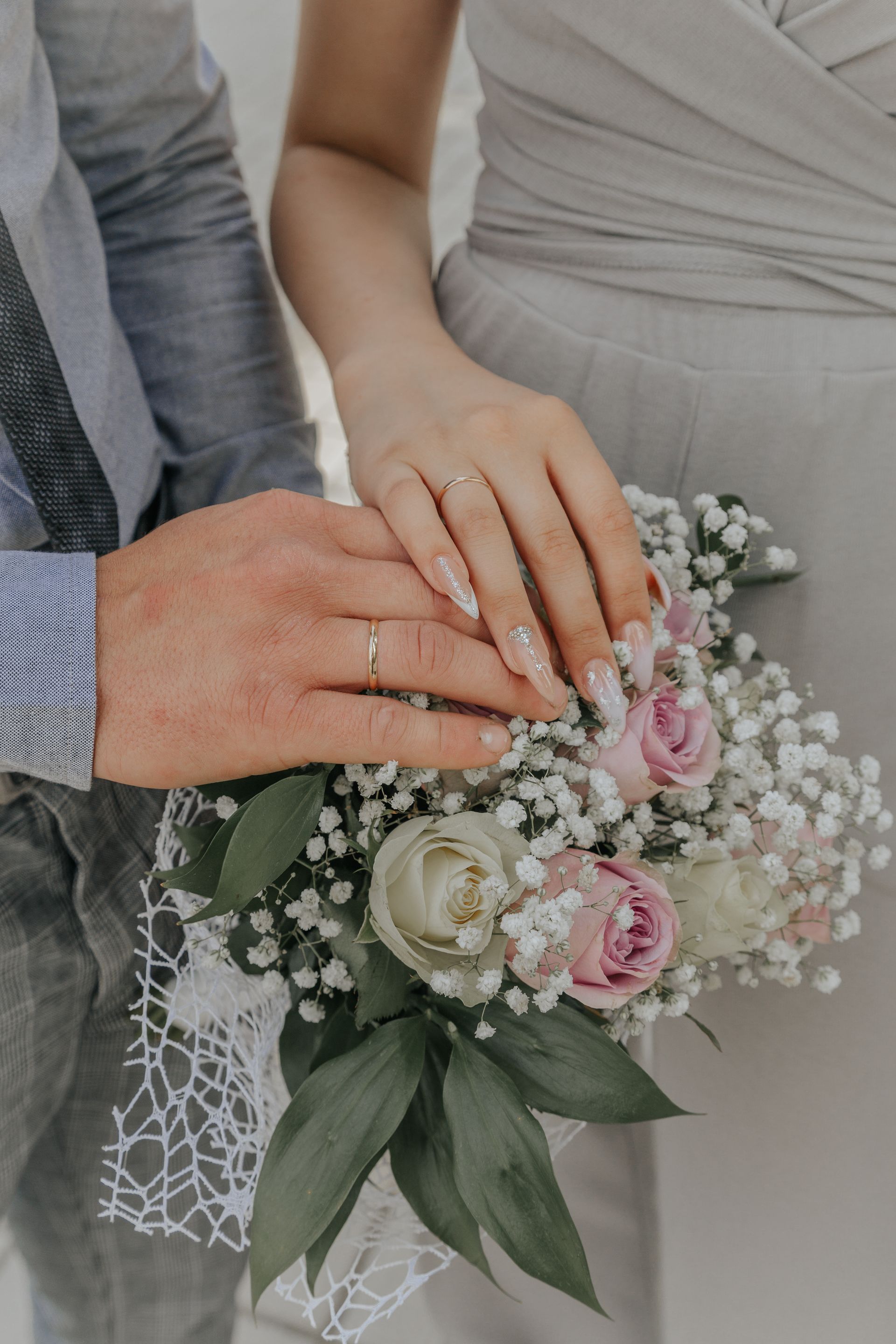 A bride and groom are holding hands and the bride is holding a bouquet of flowers.