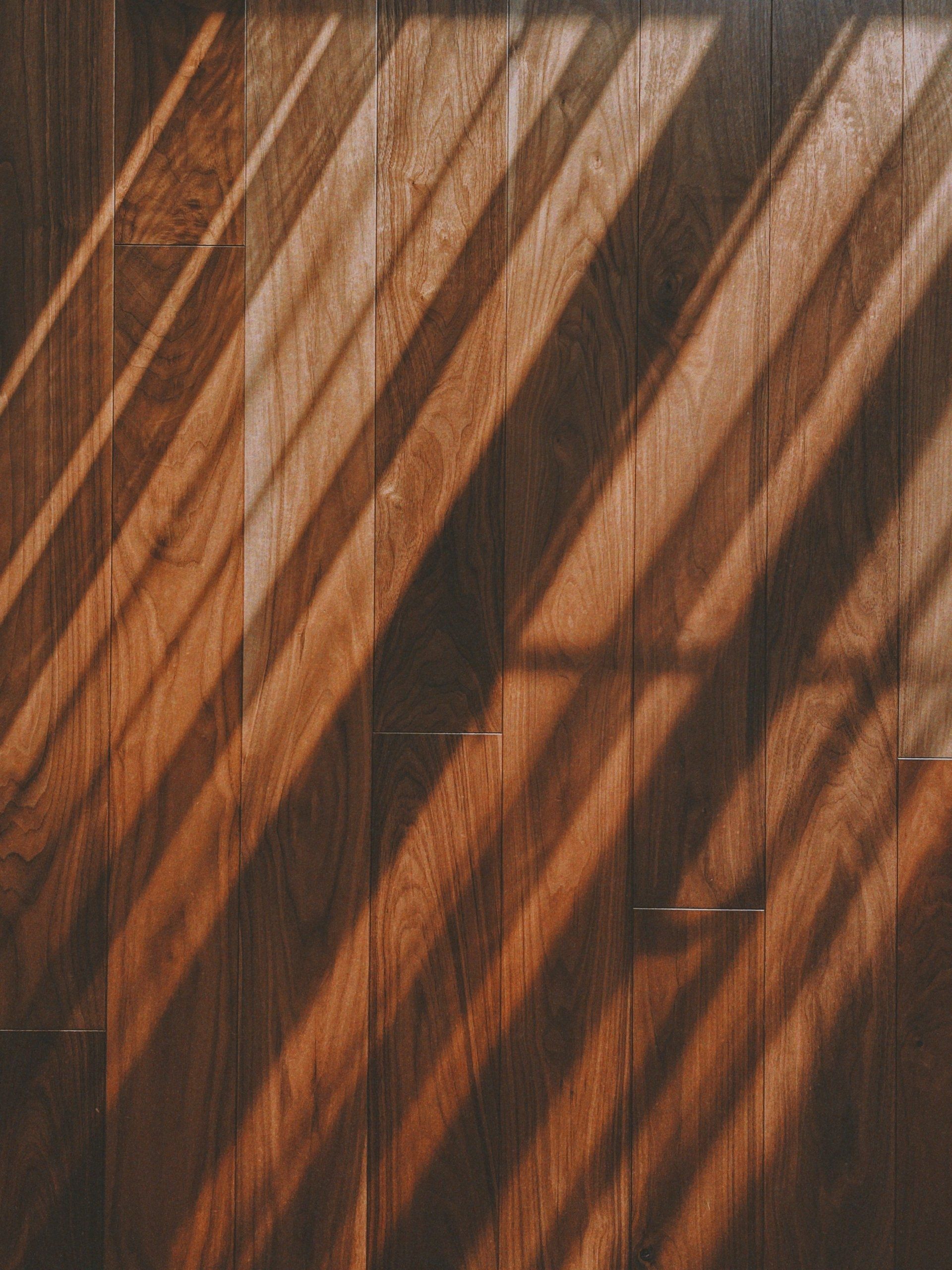The sun is casting a shadow on a wooden floor.