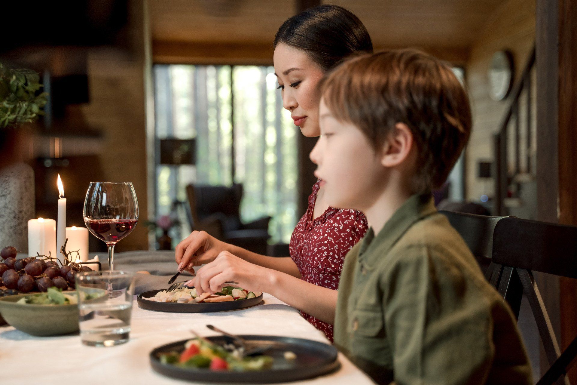 A woman and a child are sitting at a table eating food.