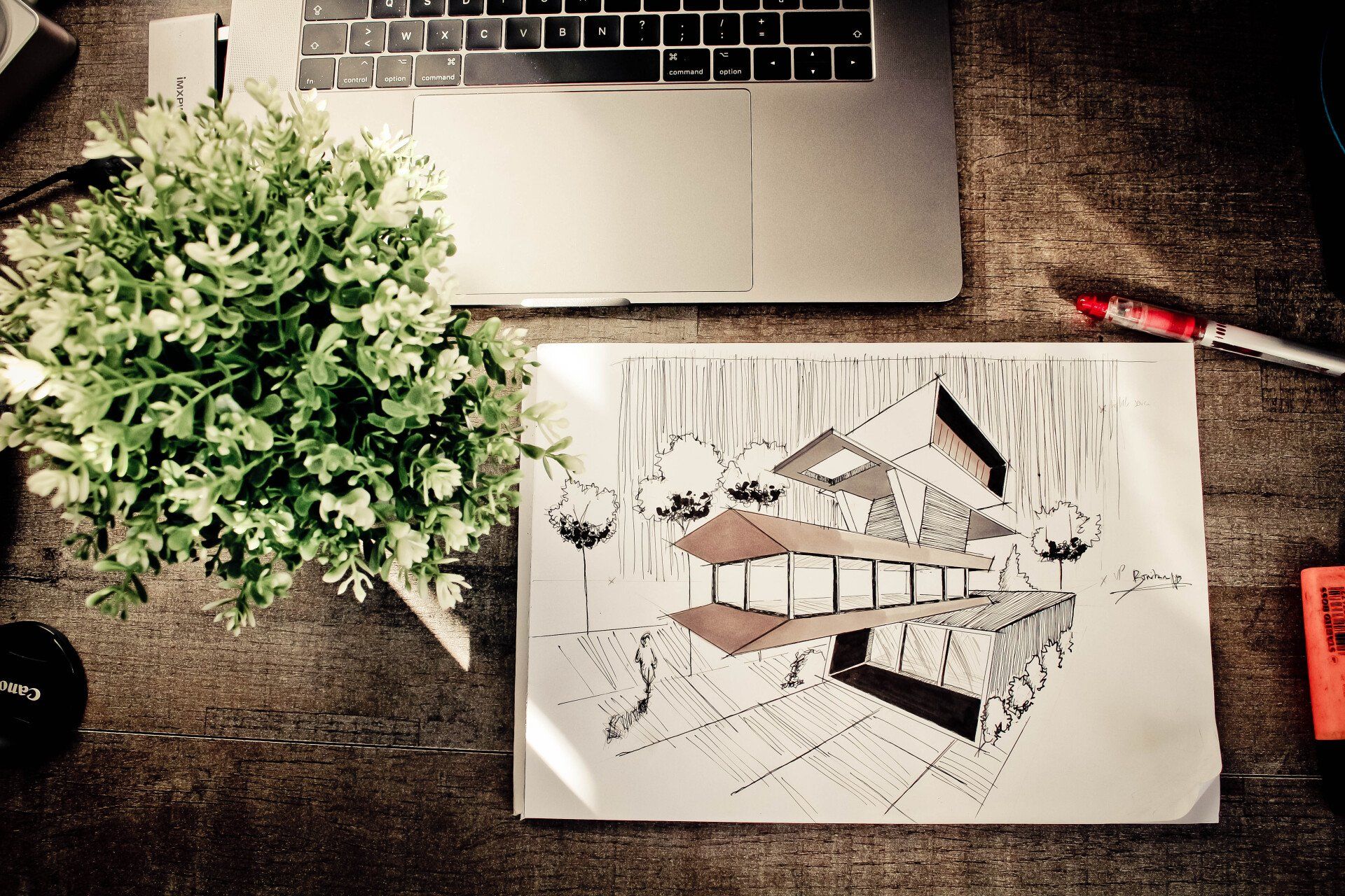 a drawing of a house is on a table next to a laptop