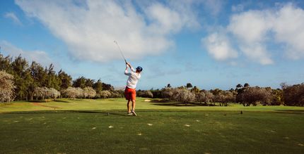 A man is swinging a golf club on a golf course.