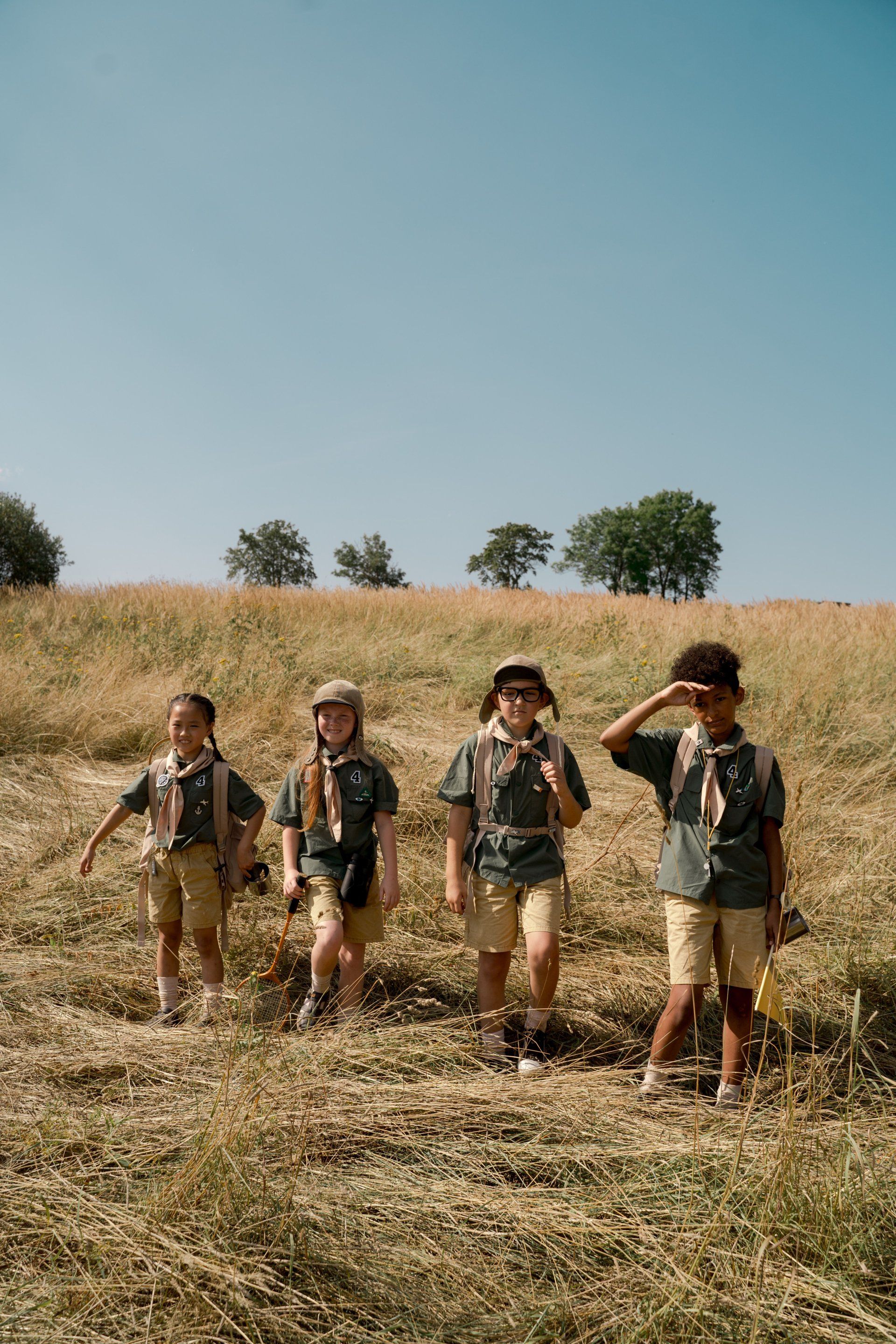 A group of boy scouts are walking through a field.