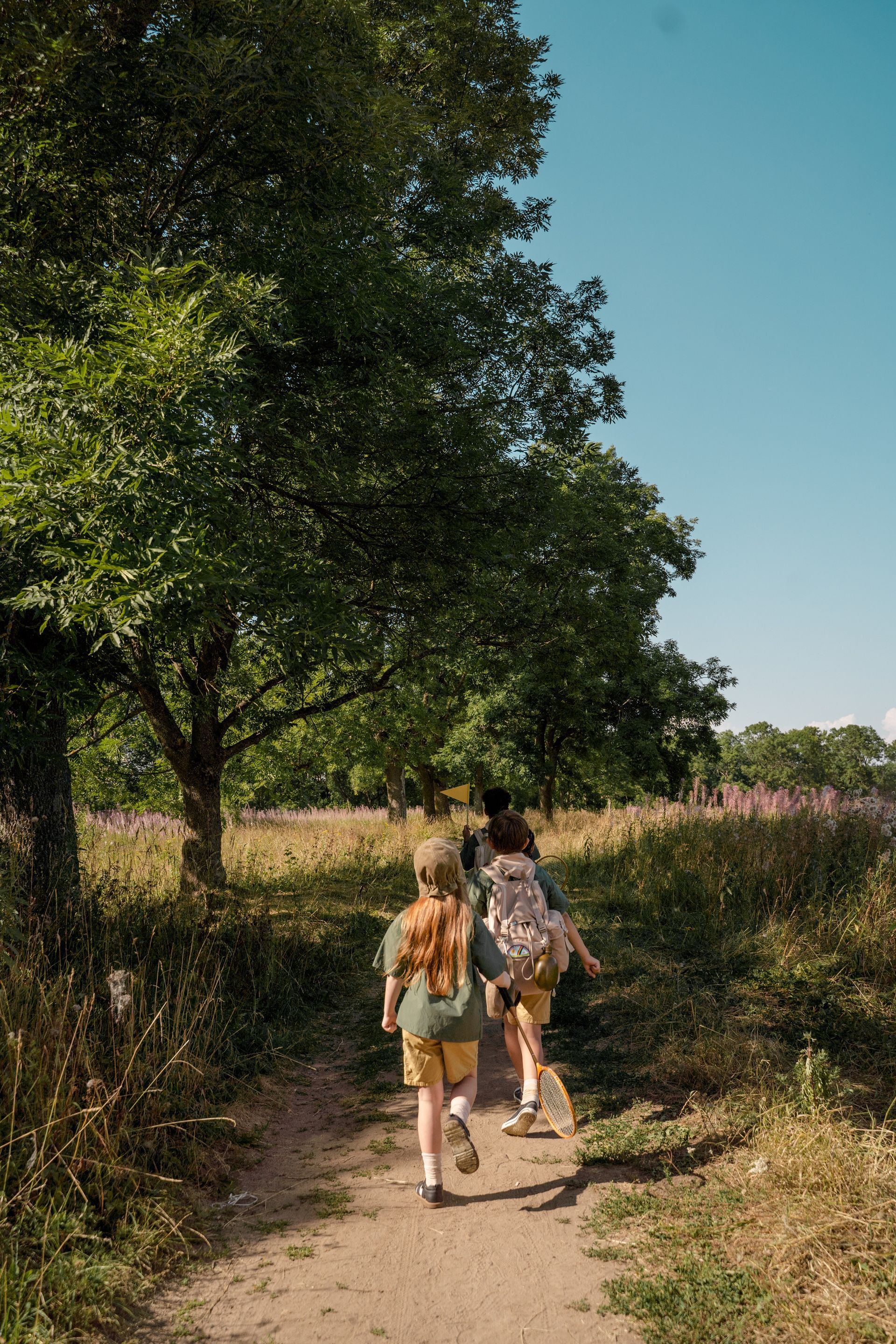 a group of children are walking down a dirt path
