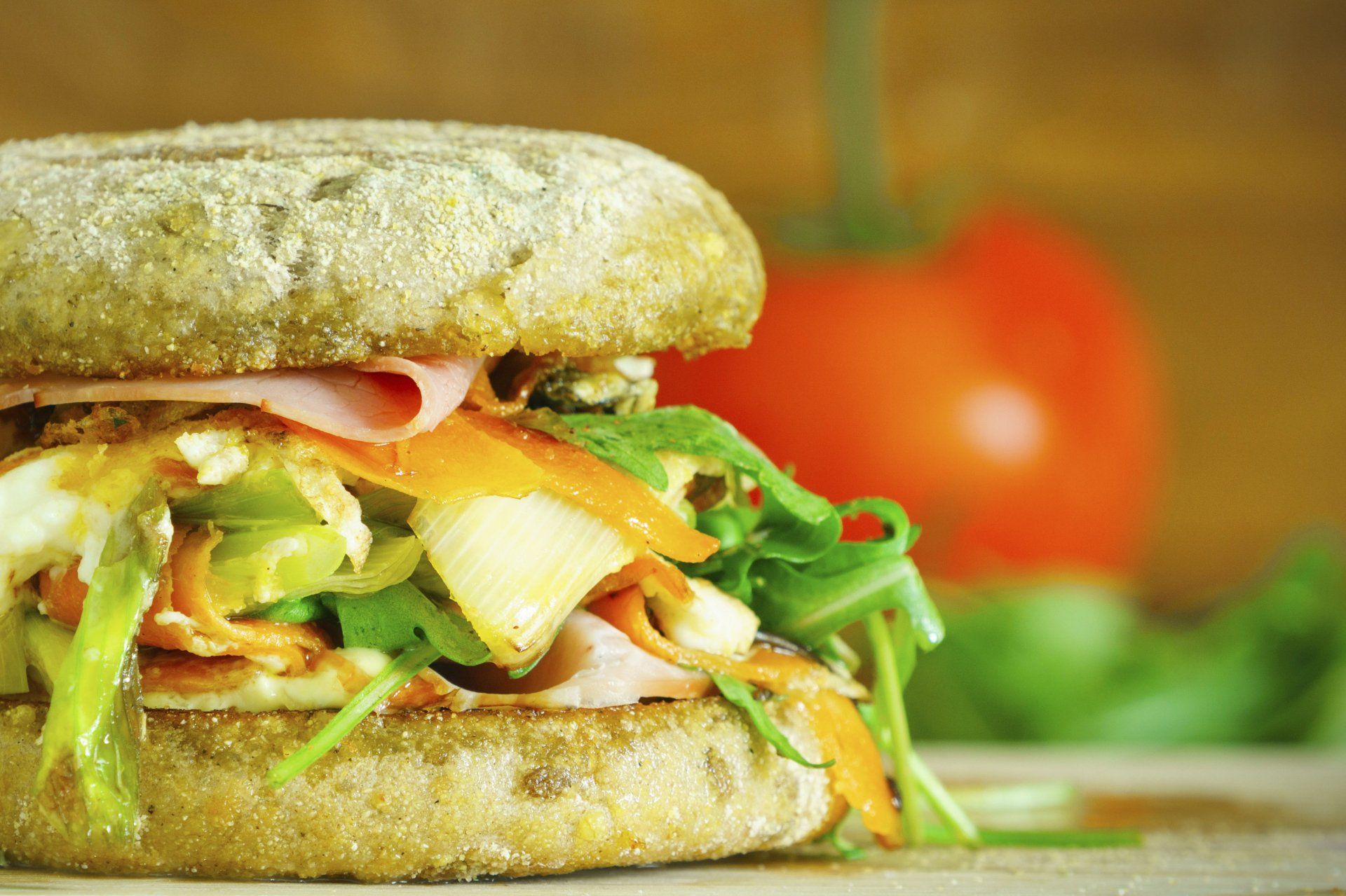 A close up of a sandwich with a tomato in the background