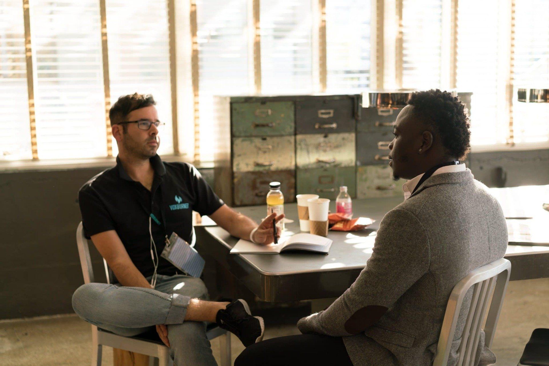 two men are sitting at a table having a conversation representing individual counseling sessions at Healing Our Trauma KC