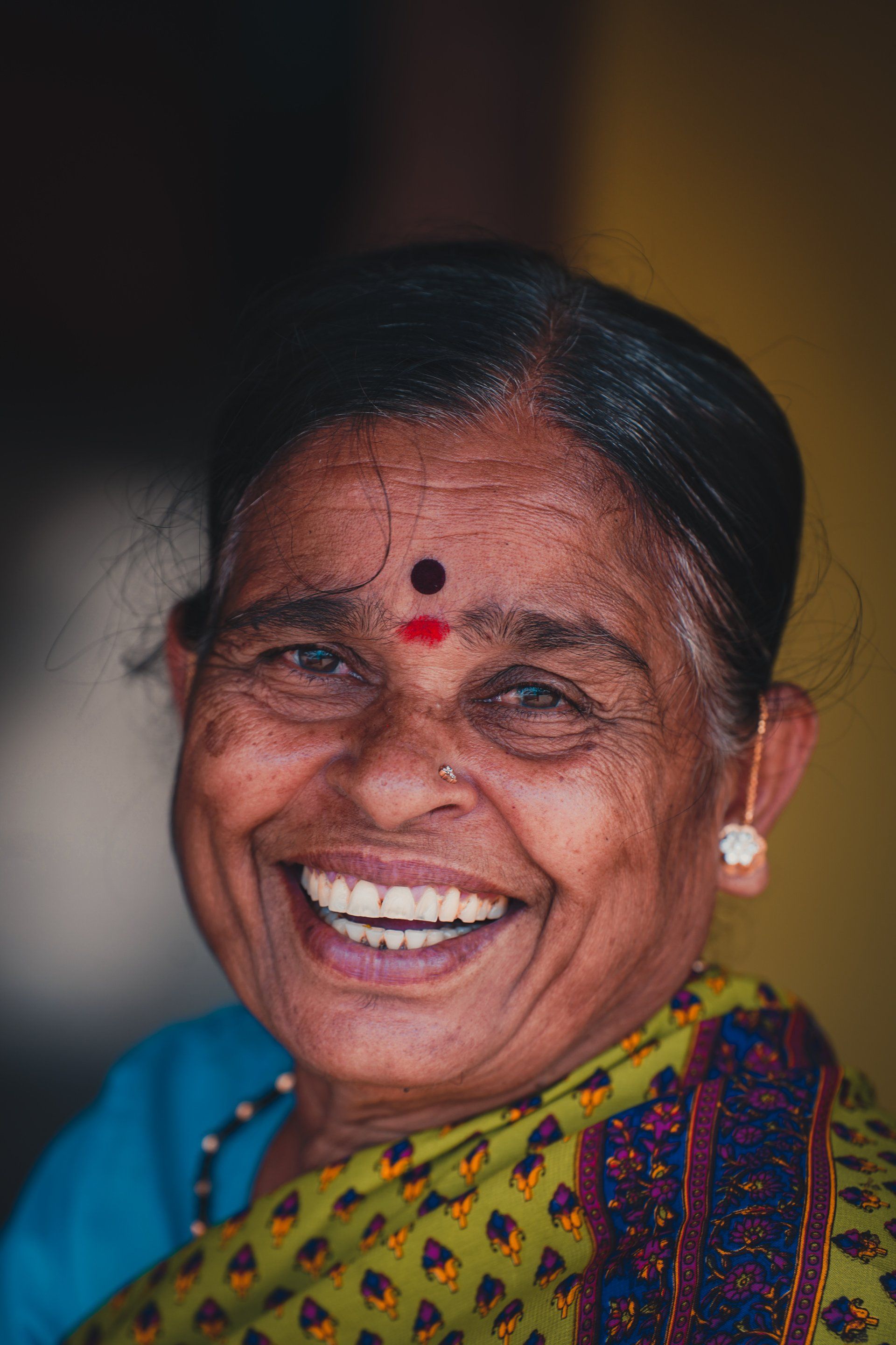 A close up of a woman smiling with a red dot on her forehead.